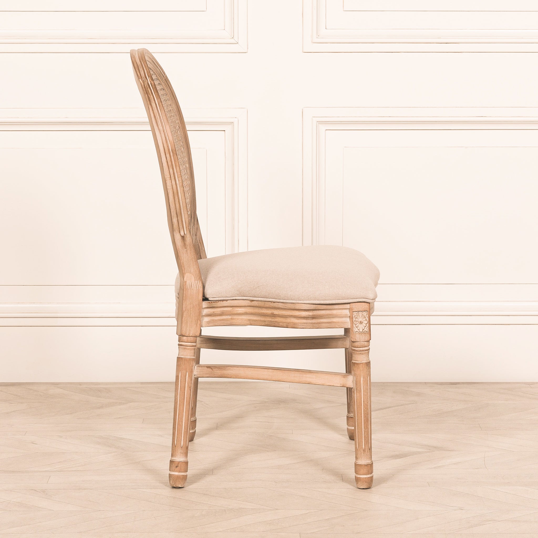 Side profile of the Camille French Louis Linen Upholstered Dining Chair displaying its elegant curved frame, carved wooden legs, oval cane backrest and generously padded linen seat.