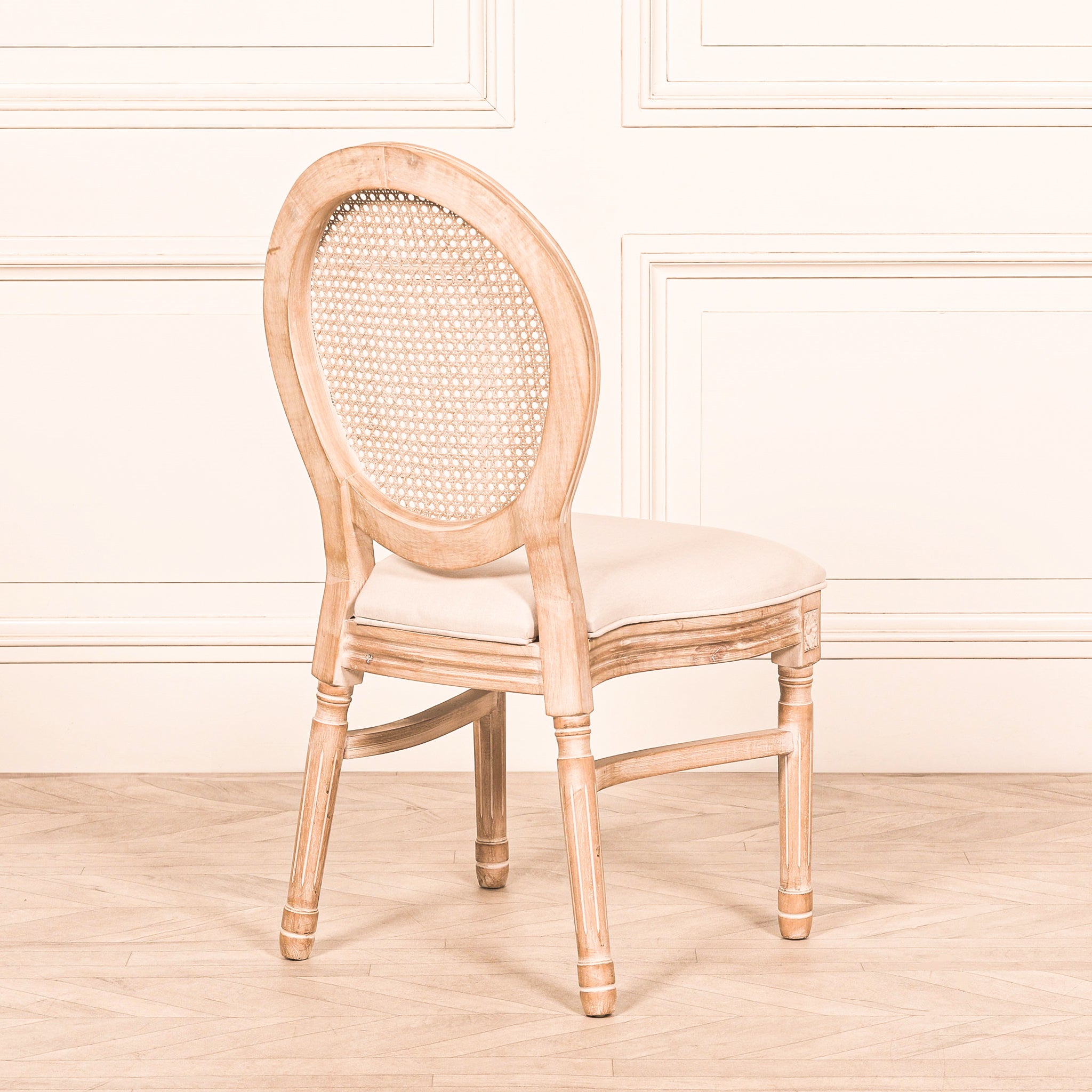 Rear three-quarter view of the Camille French Louis Linen Upholstered Dining Chair with Light Washed Wood Frame displaying the oval woven cane backrest, carved legs and classic French dining chair craftsmanship.