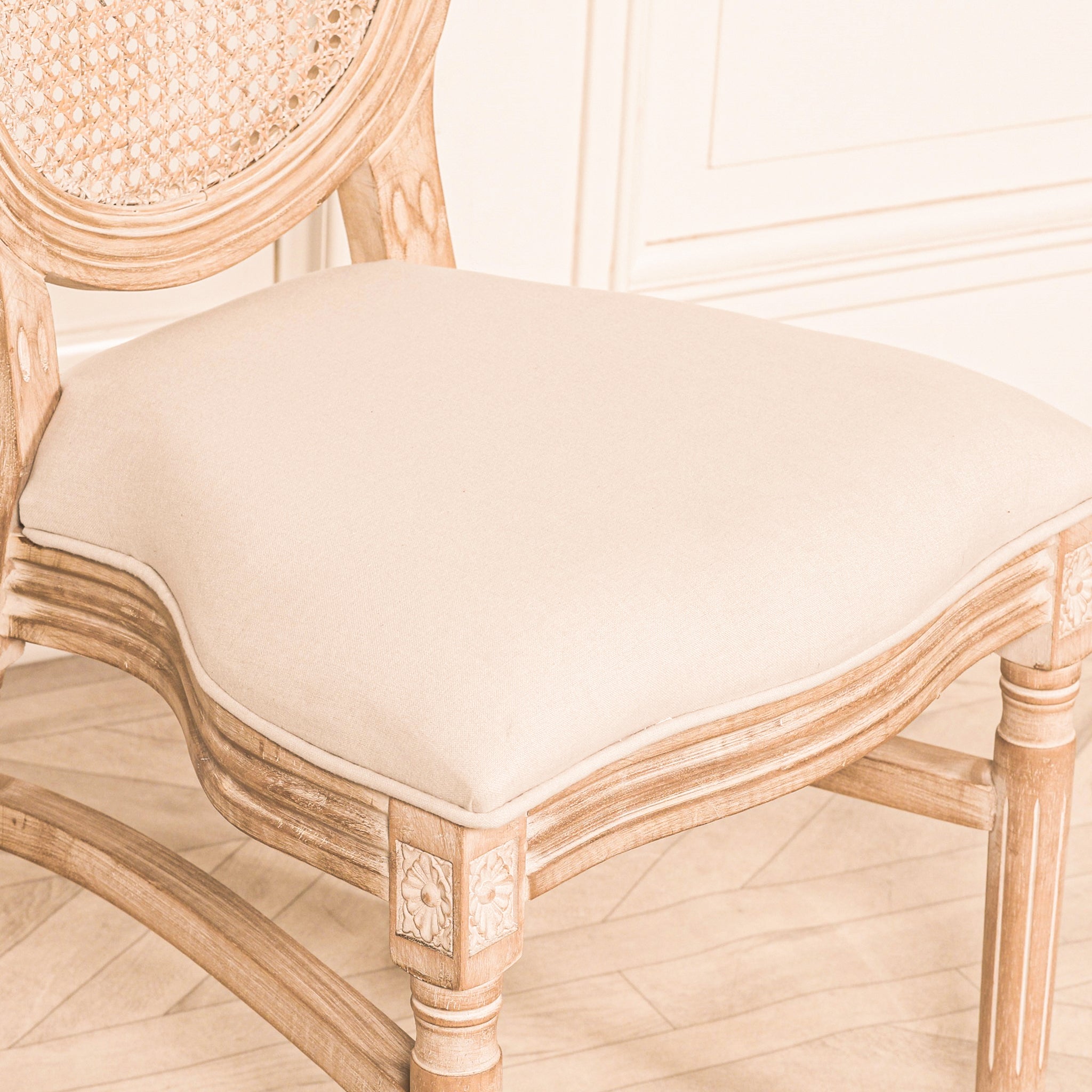 Close-up of the Camille French Louis Linen Upholstered Dining Chair with Light Washed Wood Frame featuring the premium linen upholstered seat, carved apron, decorative floral corner blocks and traditional French detailing.