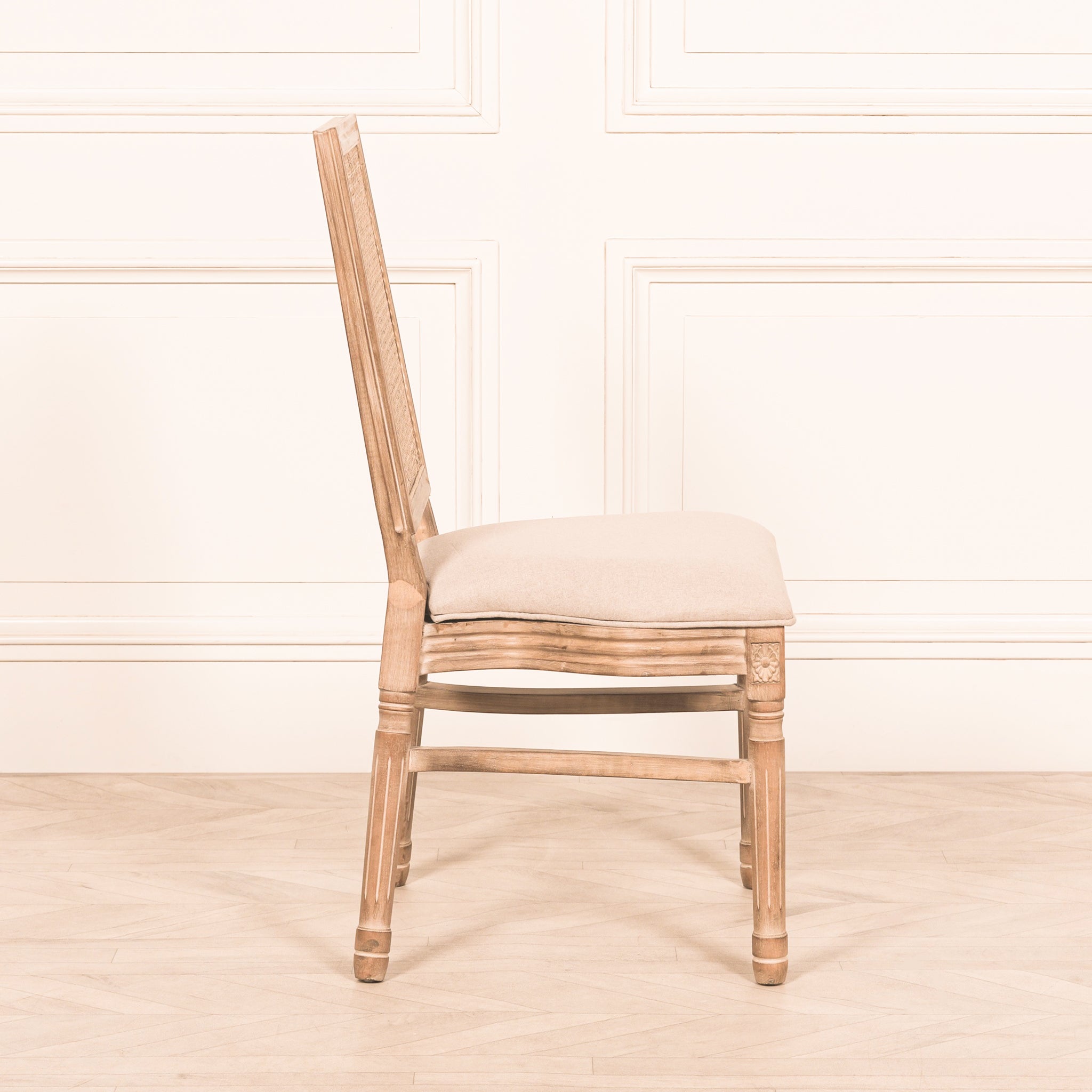 Side profile of the Camille French Louis Rattan Back Dining Chair showcasing the curved linen upholstered seat, carved wooden frame and elegant French Louis silhouette.