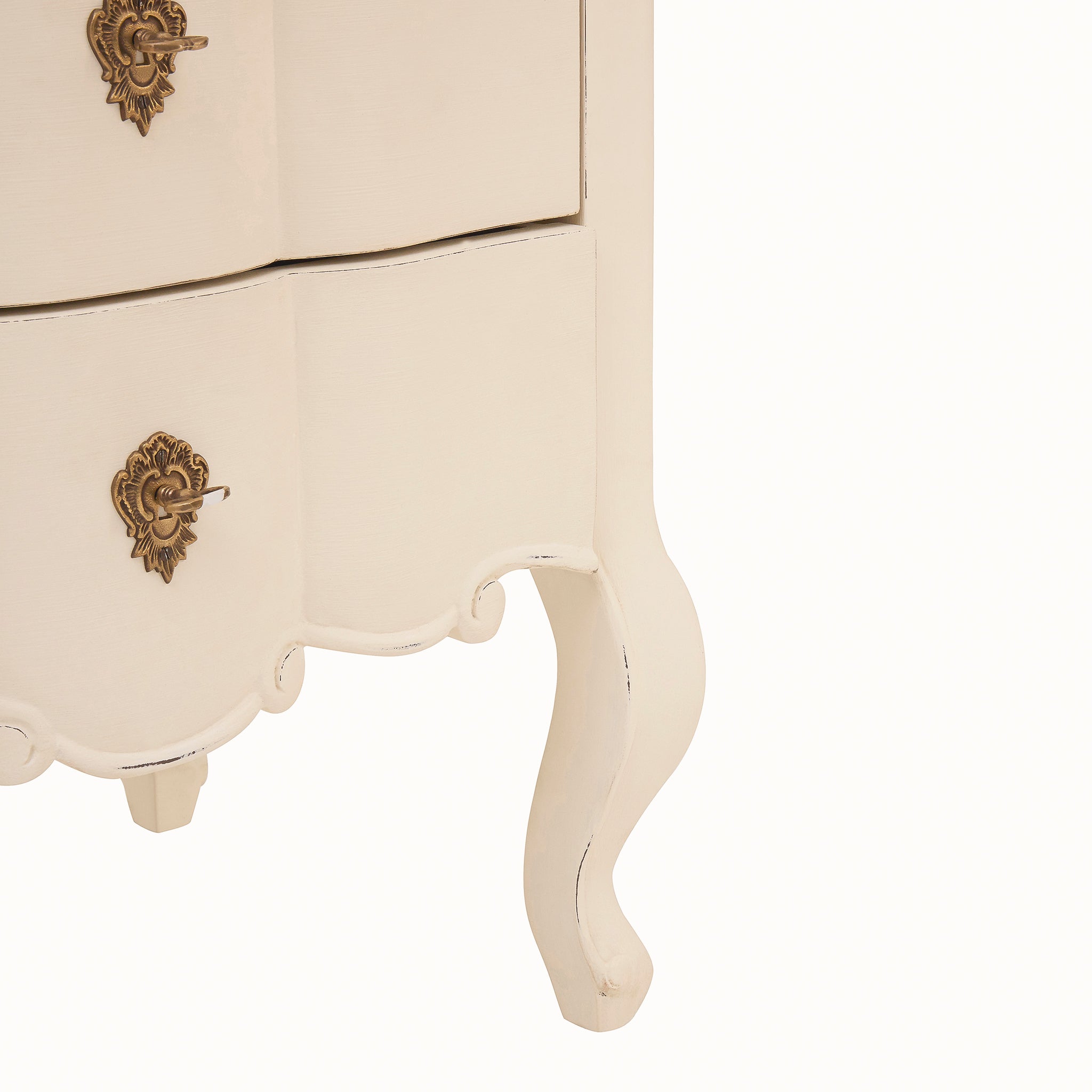 Detail of the Camille white chest of drawers showing its ornate antique brass handles, scalloped lower apron and elegant curved cabriole-style leg with subtly distressed detailing.