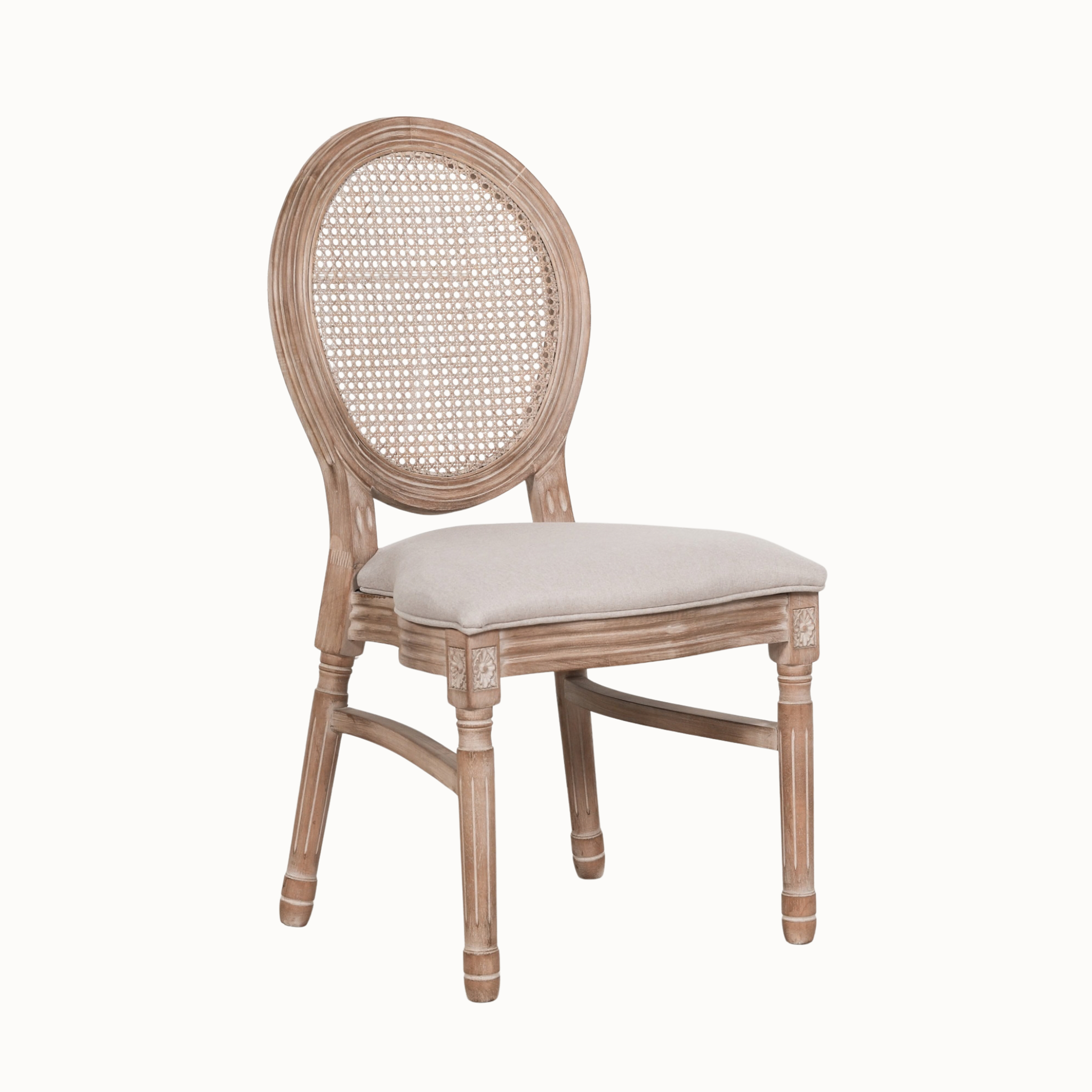 Angled view of Camille linen dining chair showing carved wooden frame and cane back on a plain white background.