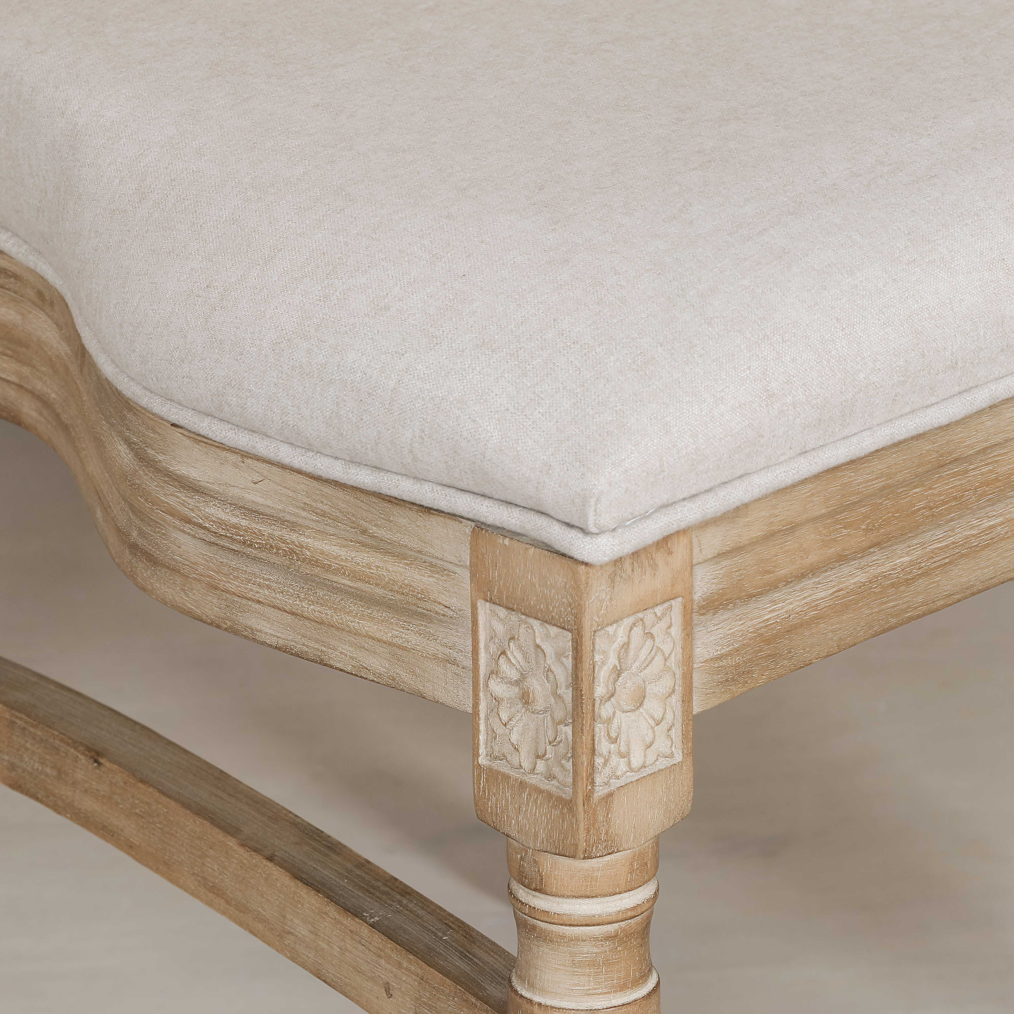 Close-up of Camille linen upholstered seat and carved light wood frame against a neutral background.