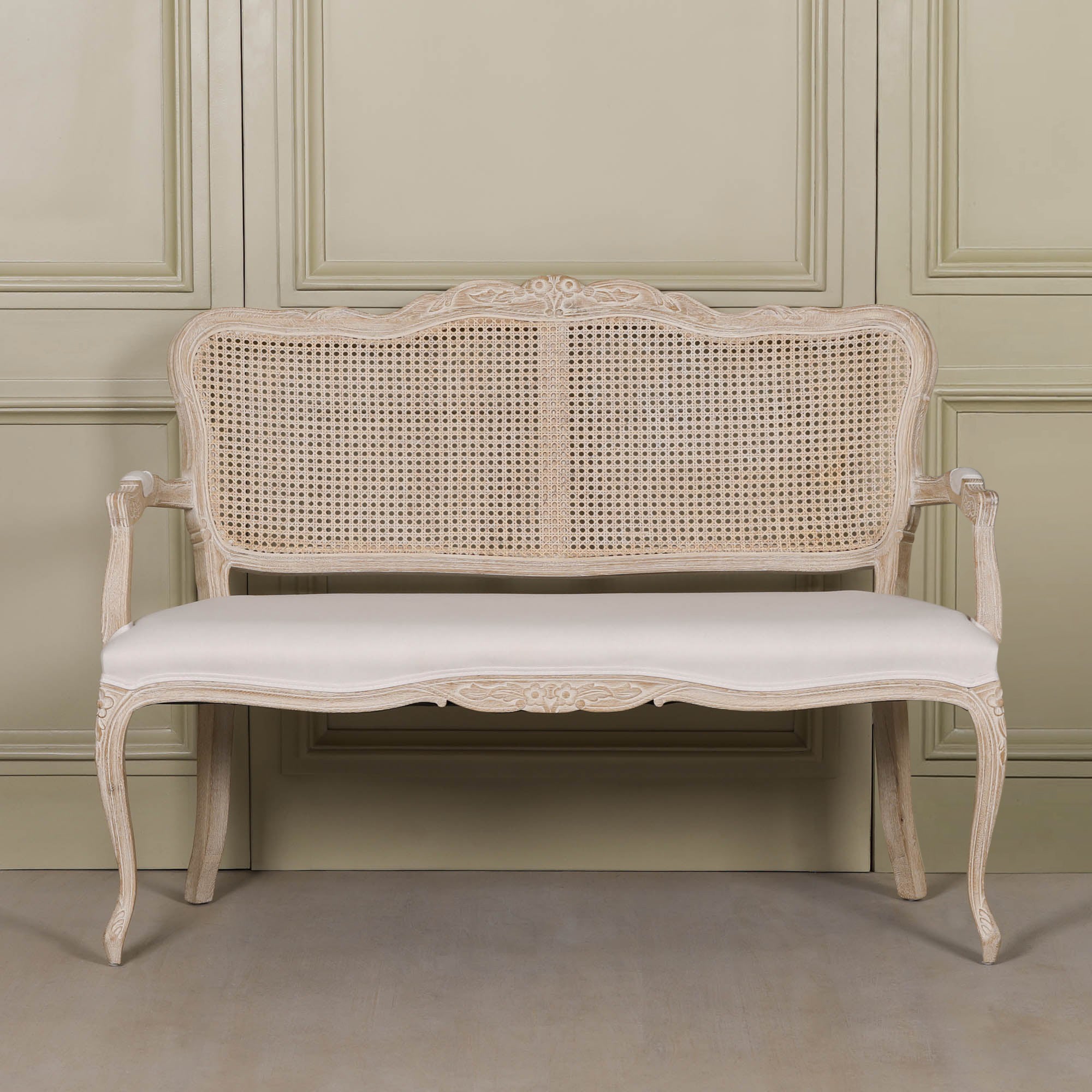 Front view of Camille Louis 2 seater settee with carved birch wood frame, cane back and cream linen upholstery.