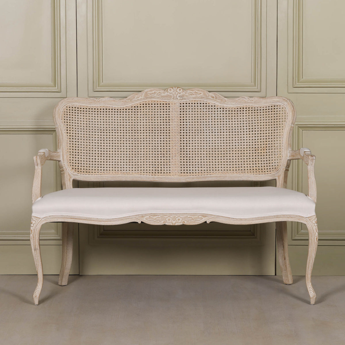 Front view of Camille Louis 2 seater settee with carved birch wood frame, cane back and cream linen upholstery.