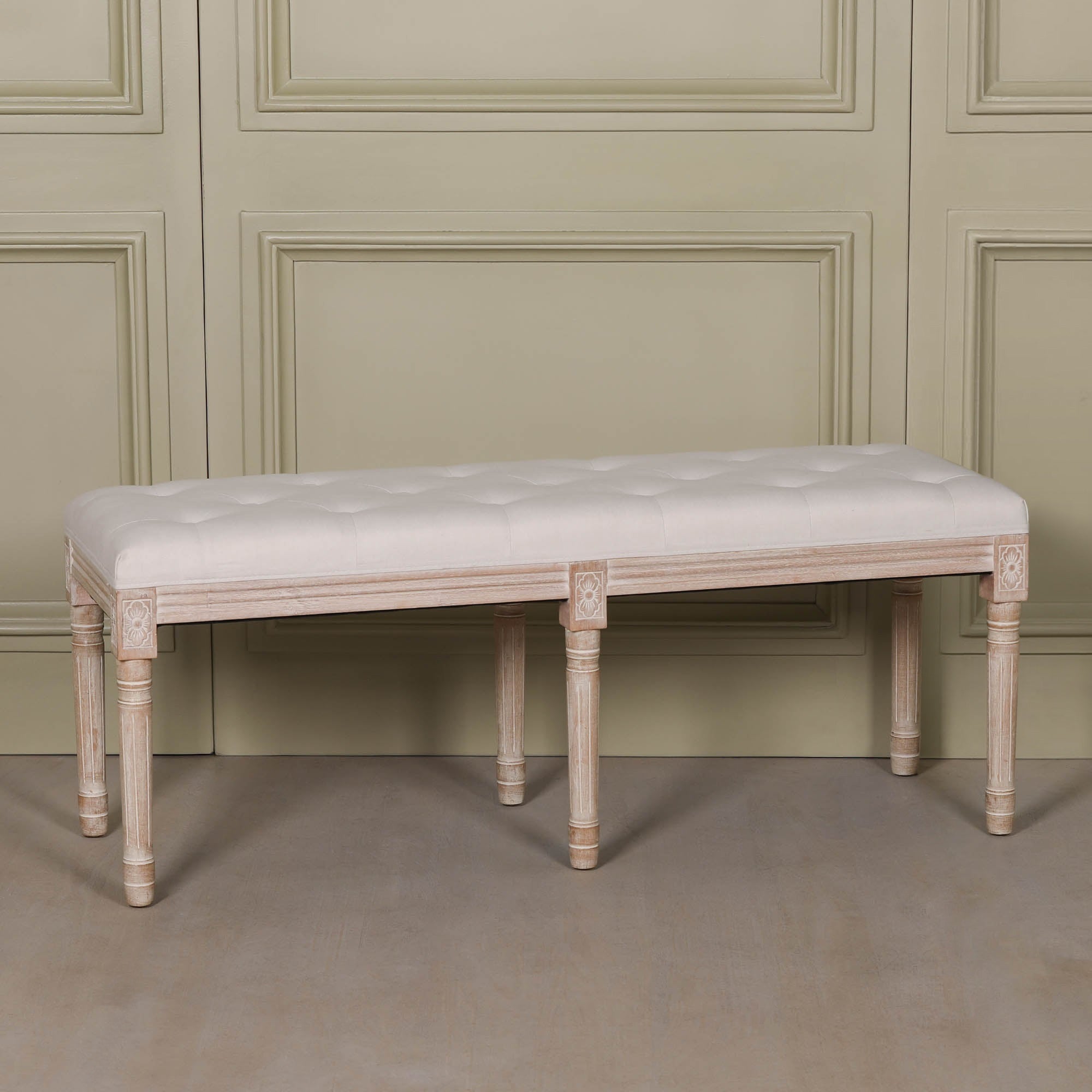 Angled view of the Camille Louis Upholstered Bench featuring a beige button tufted linen seat, hand-carved washed birch wood frame and turned legs, a timeless French Louis style bench ideal for bedrooms, hallways and dining spaces.