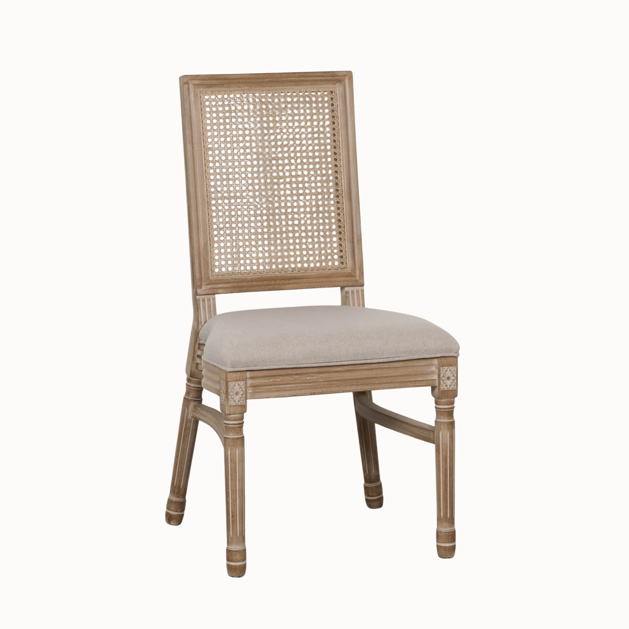 Angled view of Camille rattan back dining chair with linen upholstered seat on a clean white background.