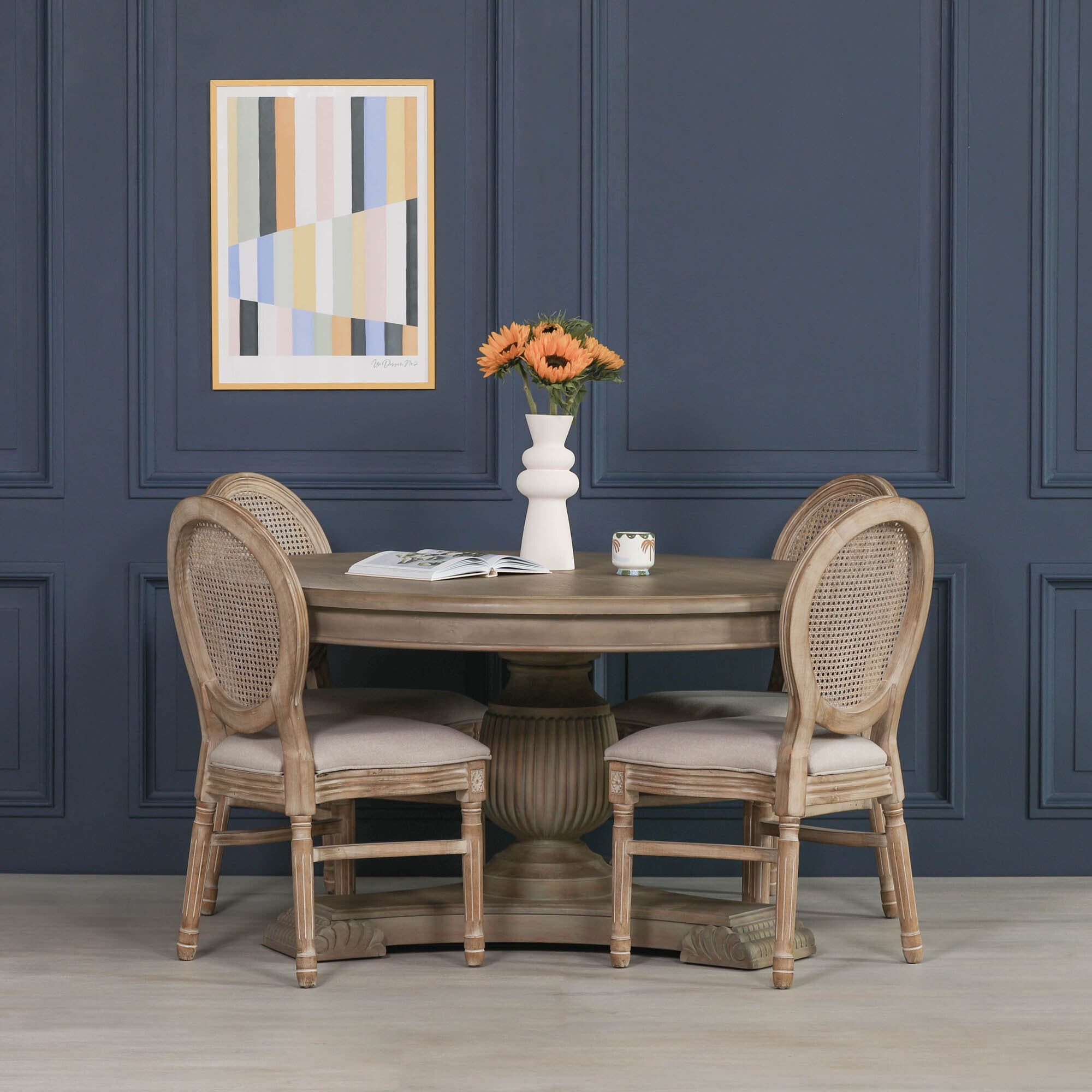 Camille Round Pedestal Dining Table 150cm for 6 in Rustic White Cedar Wood styled with upholstered rattan dining chairs in a contemporary dining room, highlighting the spacious round tabletop, fluted pedestal base and elegant farmhouse dining furniture for six people.