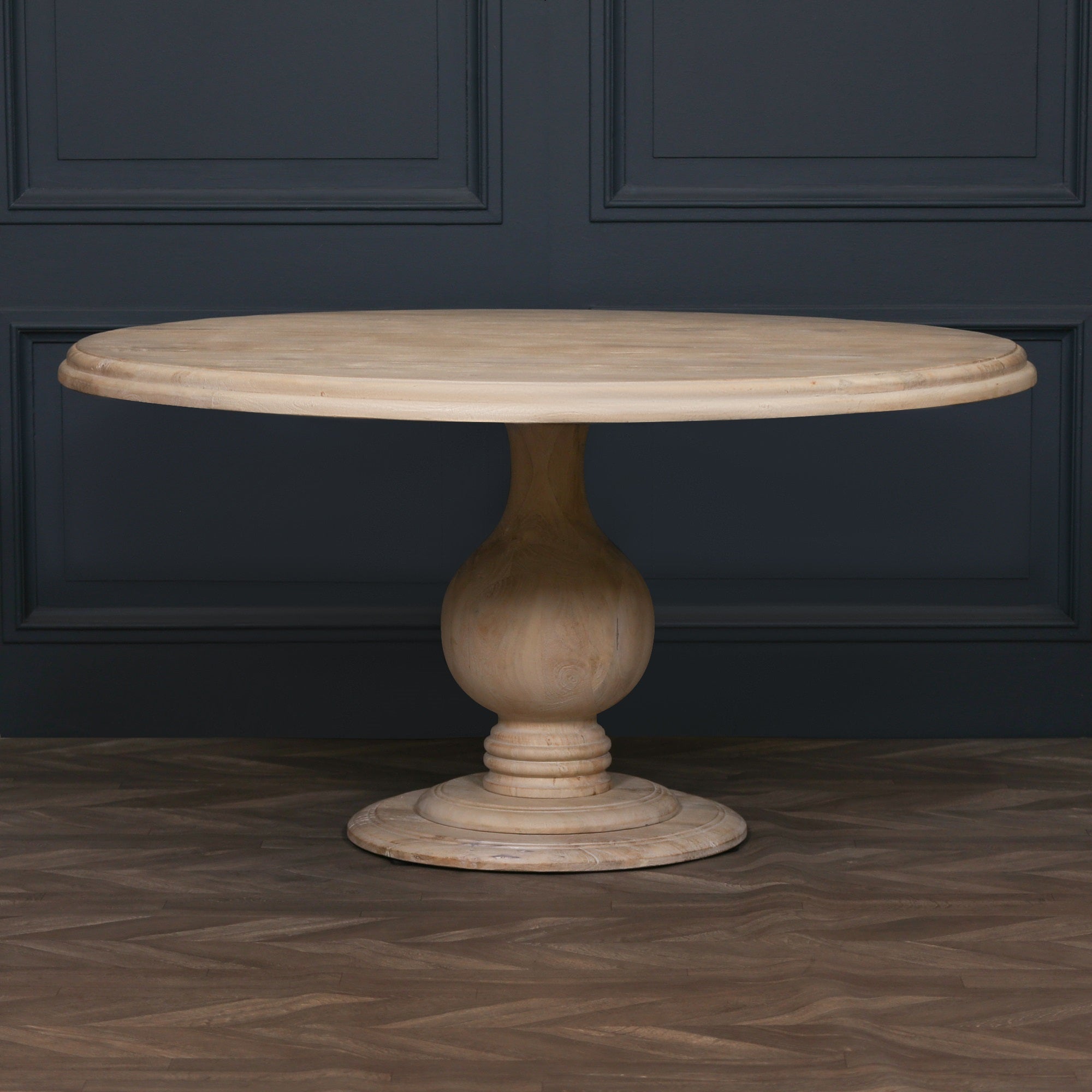 Camille Round Pedestal Dining Table 152cm for 6 in Bleached Mango Wood displayed against a dark panelled wall, showcasing the statement round tabletop, sculptural pedestal base and handcrafted solid mango wood construction for luxury dining room interiors.