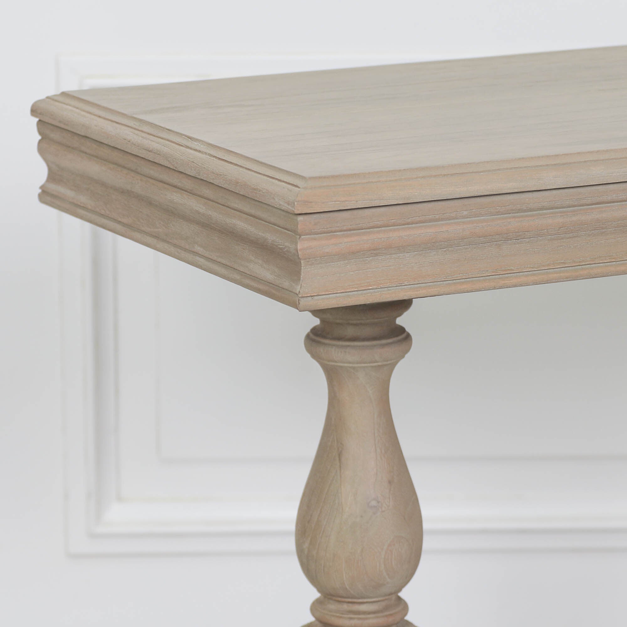 Close-up of Camille rustic white cedar console table top and turned leg against a white panelled background.