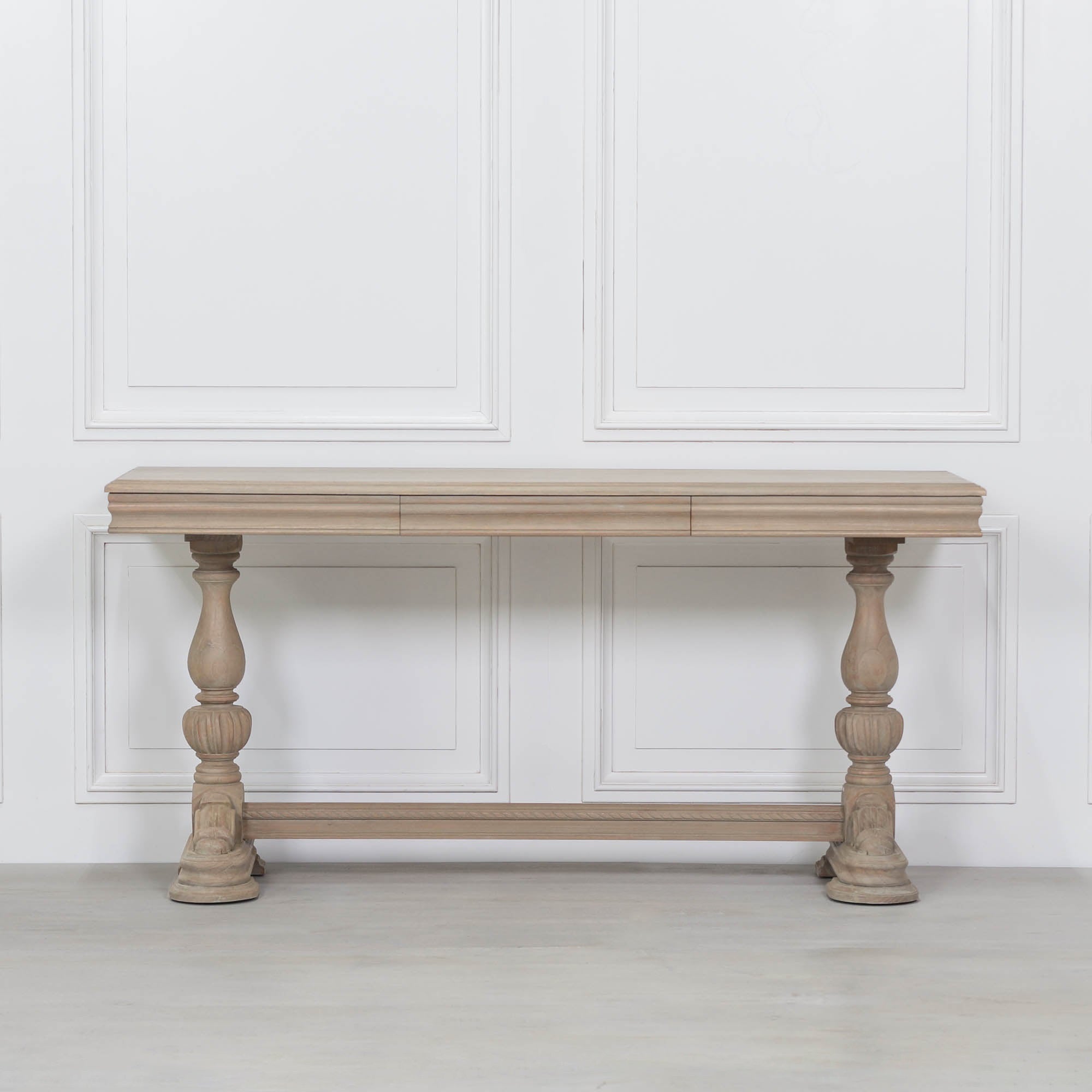 Camille carved white cedar wood console table with drawer and turned legs against a white panelled wall.