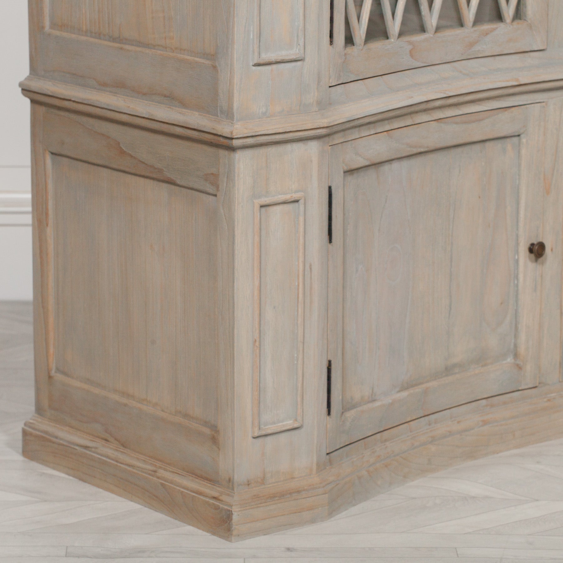 Close-up of Camille white cedar display cabinet lower storage doors on a pale wood floor.