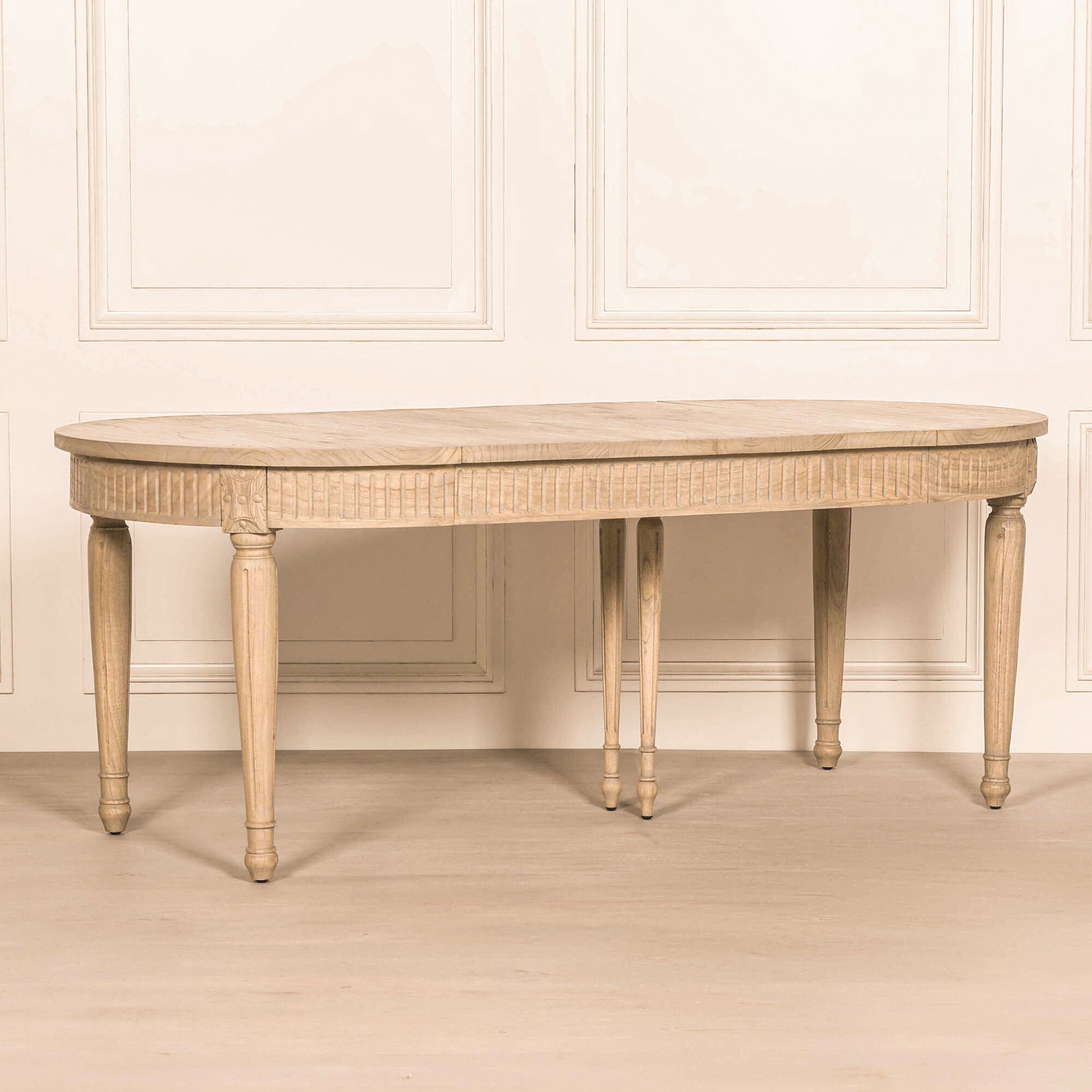 Camille White Cedar Wood Extendable Dining Table extended to 200cm against a neutral panelled backdrop, showcasing the oval extending tabletop, rustic cedar wood finish and classic carved detailing.