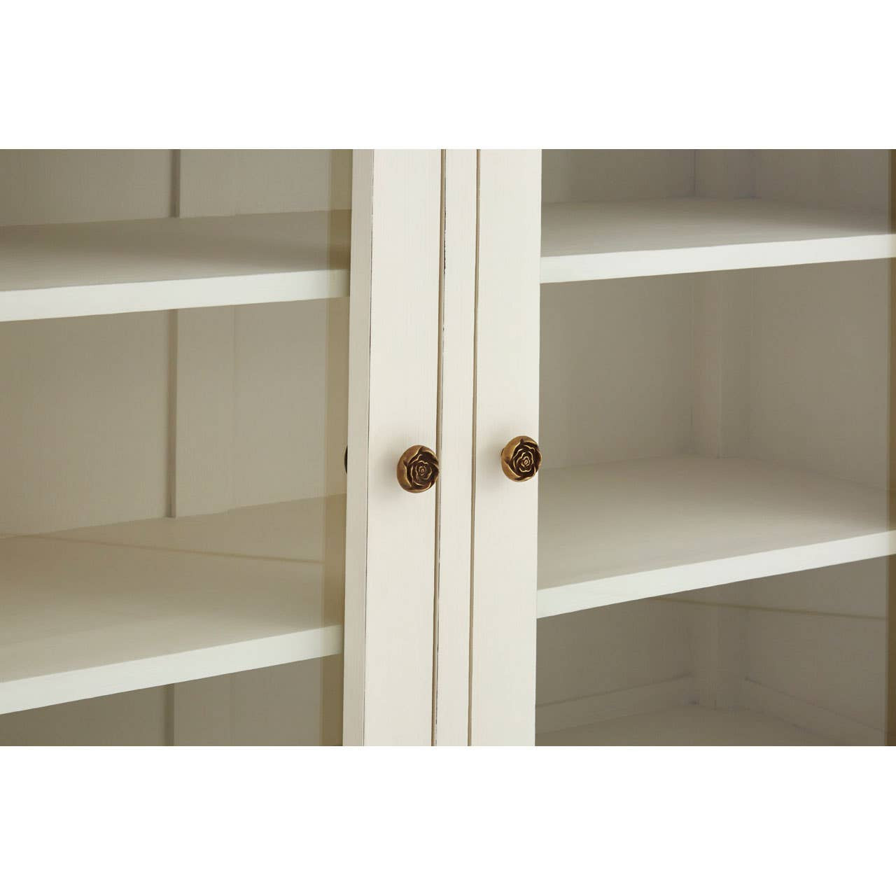 Close-up of the Camille White Display Cabinet showcasing the decorative bronze-effect flower door knobs, glazed cabinet doors, painted white finish and spacious internal shelving.