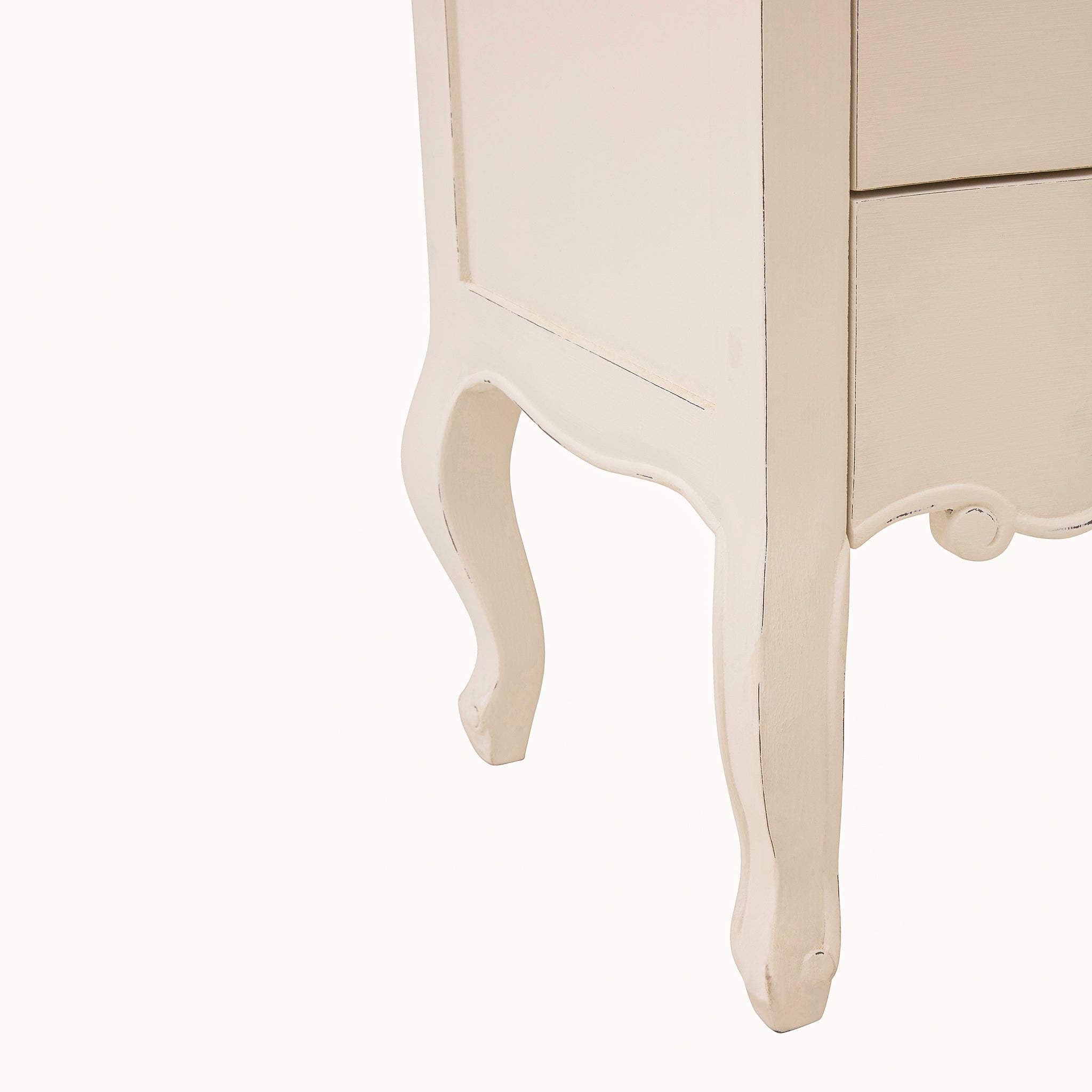 Close-up of the Camille five drawer chest of drawers showing the white painted side panel, decorative scalloped apron and elegant curved leg with subtle distressed edge detailing.