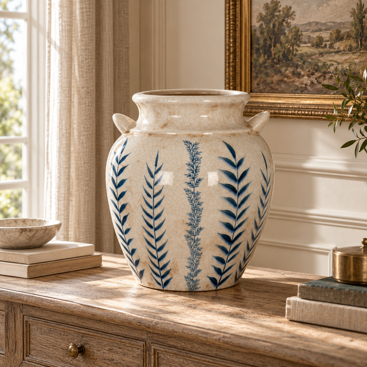 Capucine blue and white ceramic amphora vase on a rustic console in a warm sunlit neutral interior.