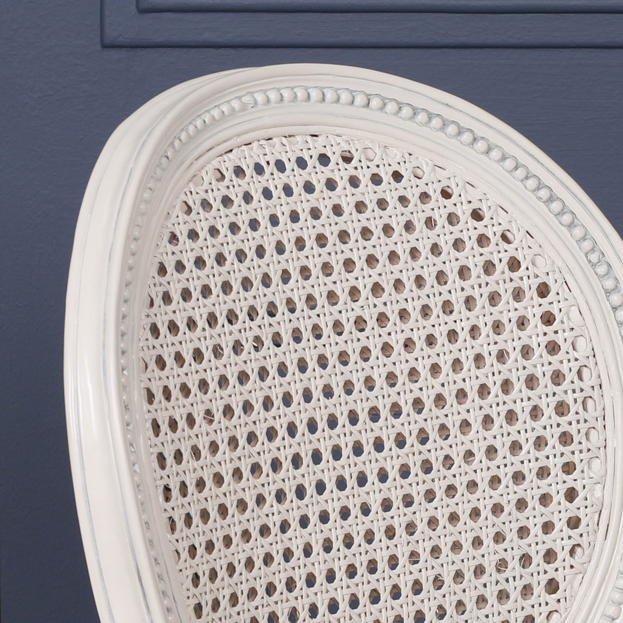 Close-up of the Céleste French Chateau Rattan Dining Arm Chair in Off-White Mahogany showcasing the oval woven cane backrest, hand-carved beaded frame and elegant French-inspired detailing.