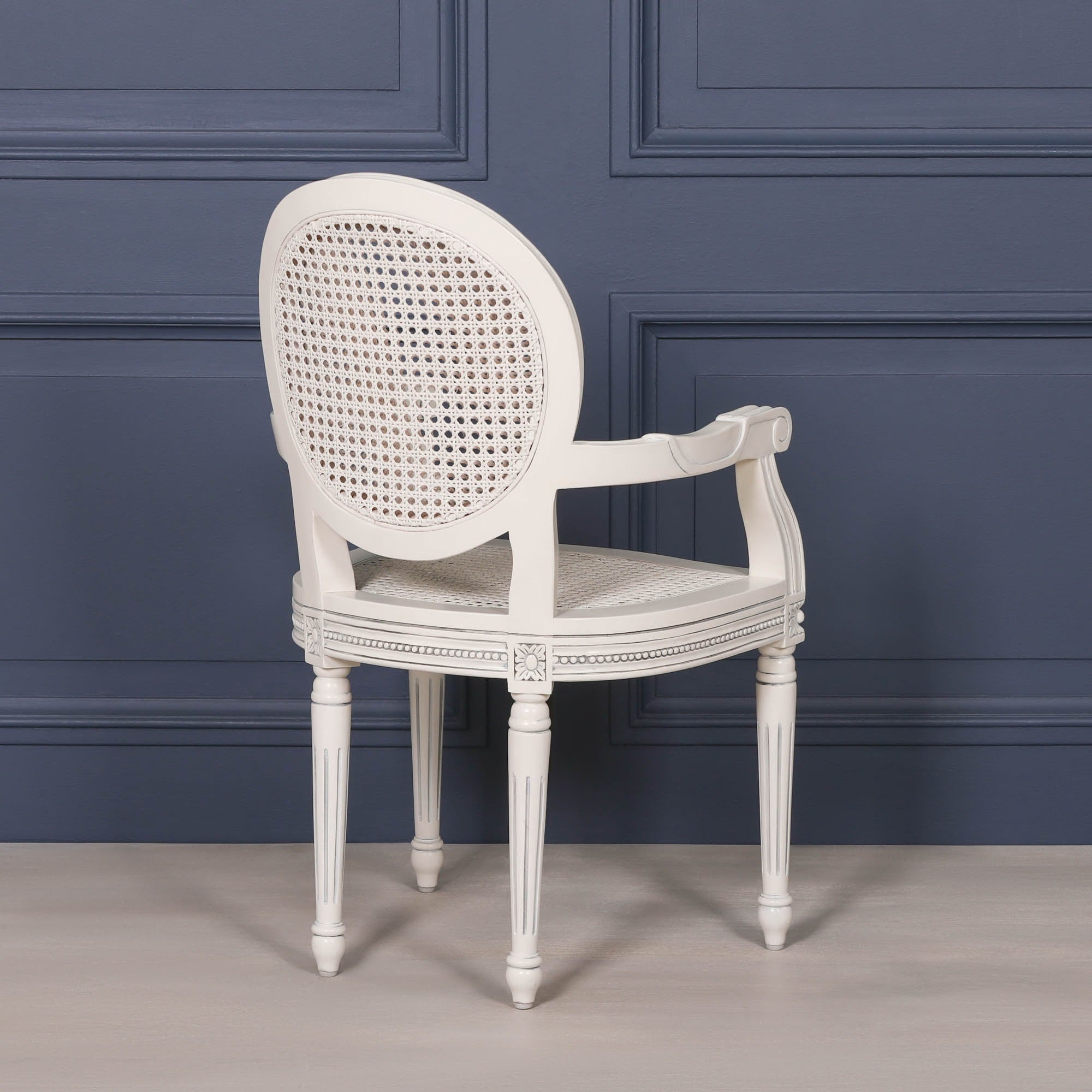 Rear angled view of the Céleste French Chateau Rattan Dining Arm Chair in Off-White Mahogany highlighting the curved oval cane back, carved frame, decorative armrests and traditional French craftsmanship.
