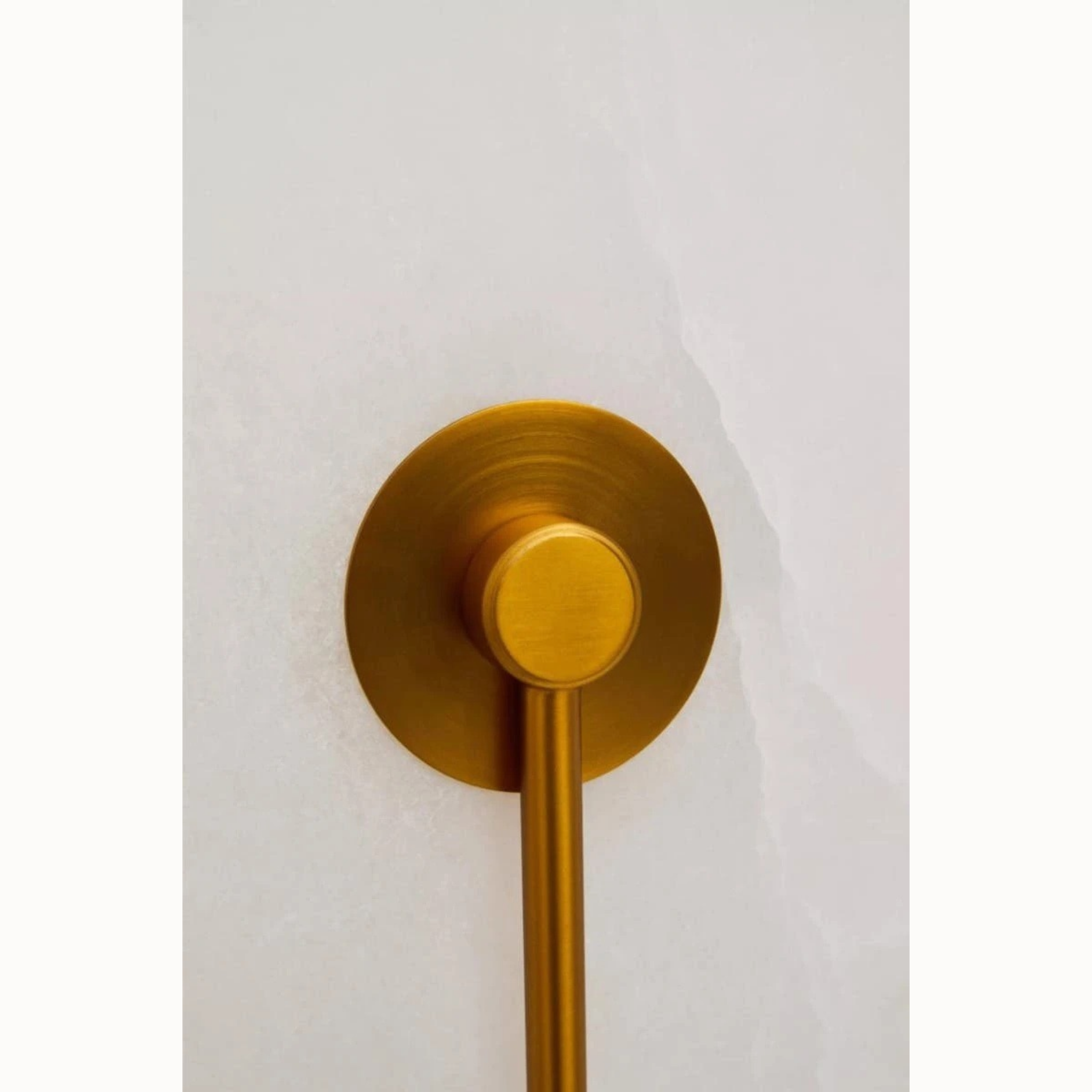 Close-up of Clovis white marble wall light with brushed gold metal fitting against a plain white background.