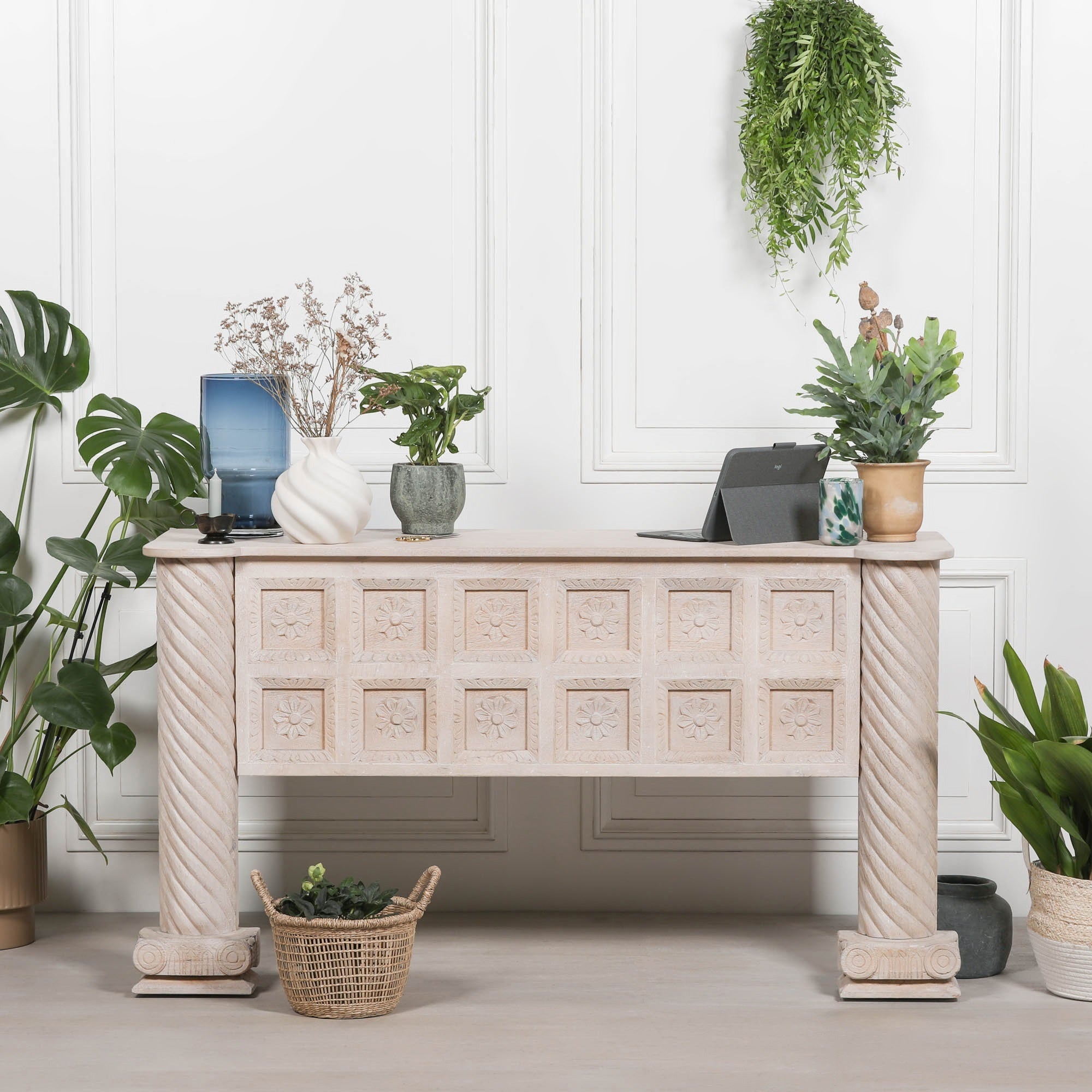 Delphine carved mango wood reception desk styled with plants against a white panelled wall