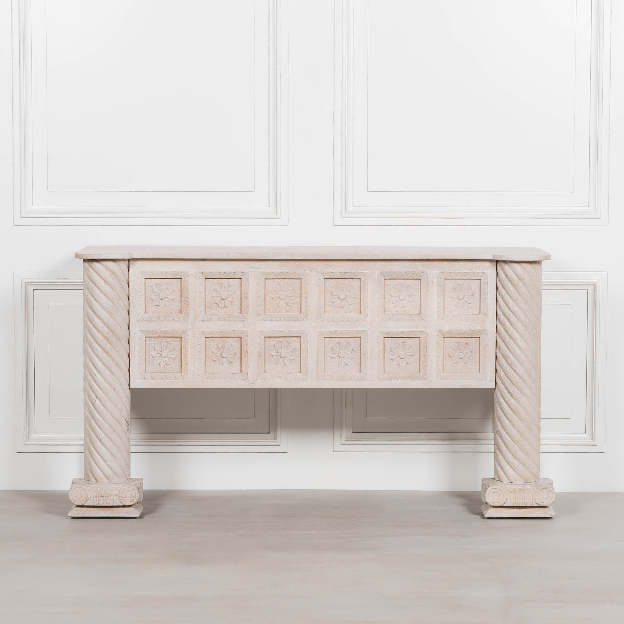 Front view of Delphine carved mango wood reception desk with floral panels against a white panelled wall