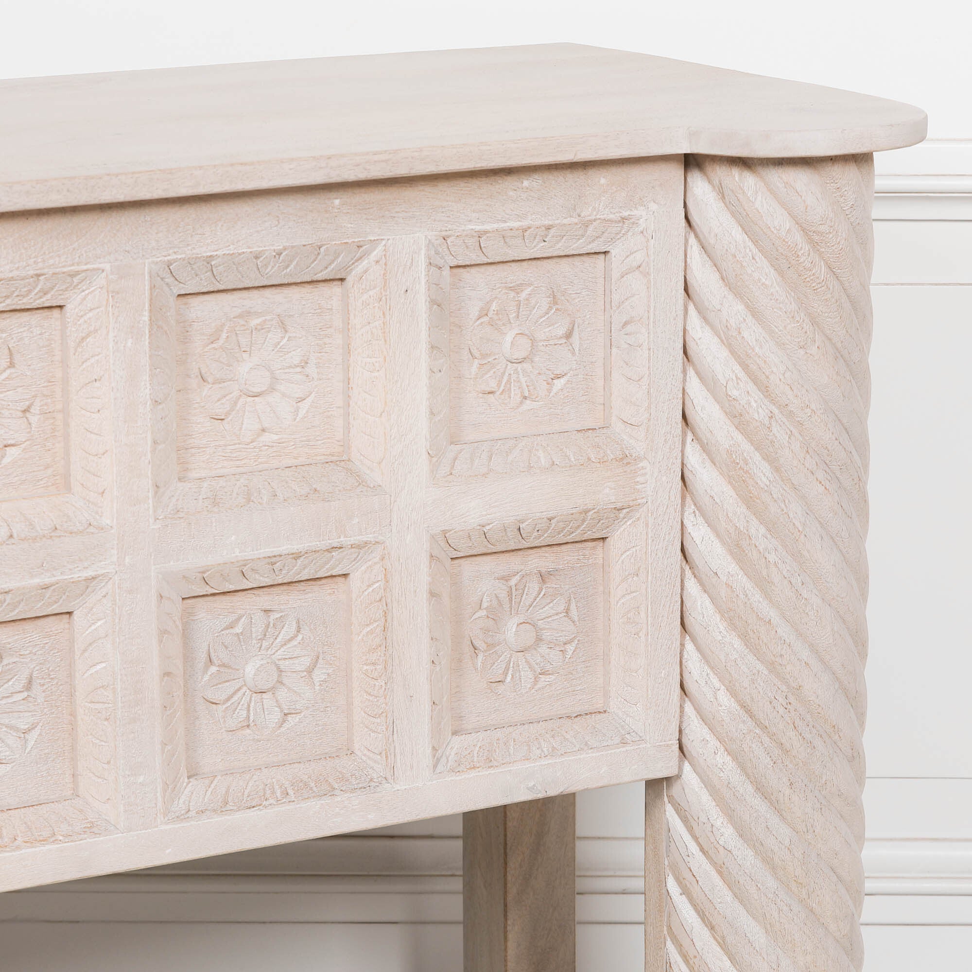 Close-up of Delphine mango wood reception desk with carved floral panels against a white panelled wall