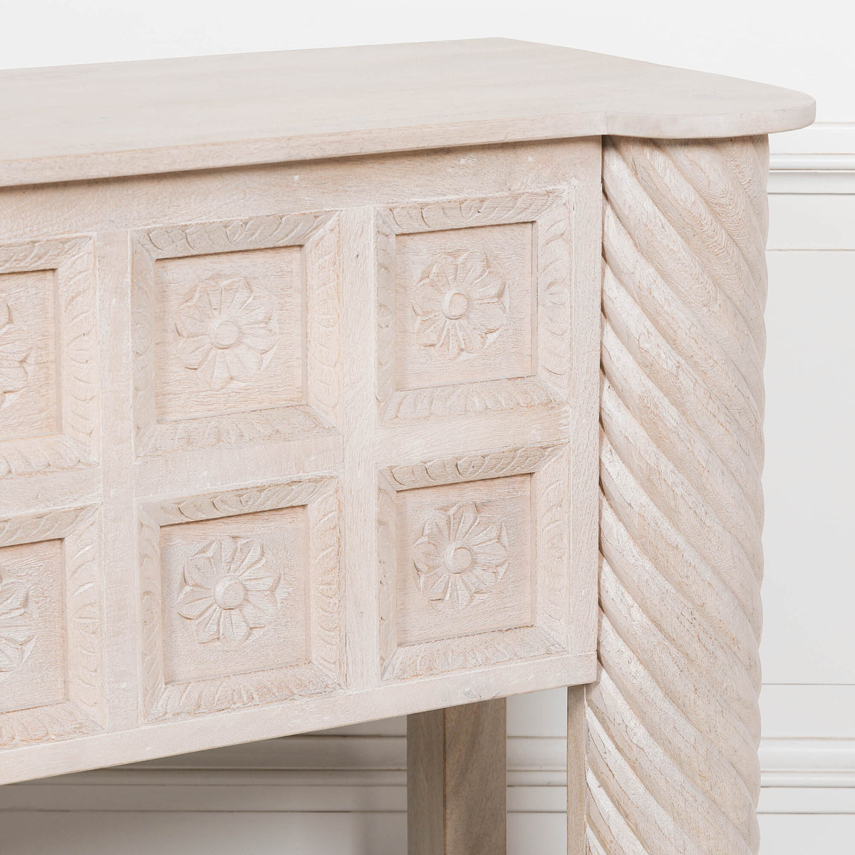 Close-up of Delphine mango wood reception desk with carved floral panels against a white panelled wall