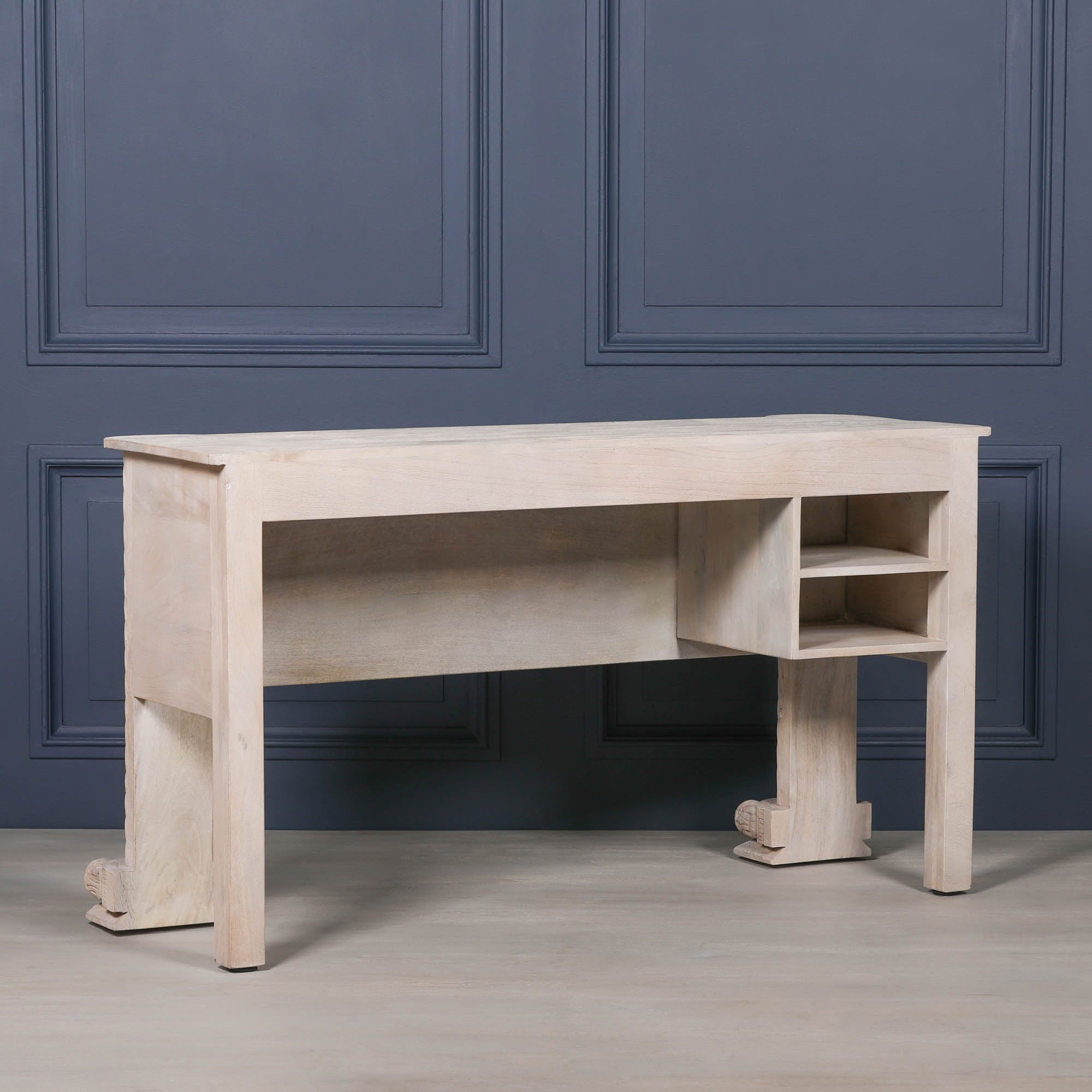 Rear view of Delphine mango wood reception desk with open storage shelves against a dark blue panelled wall