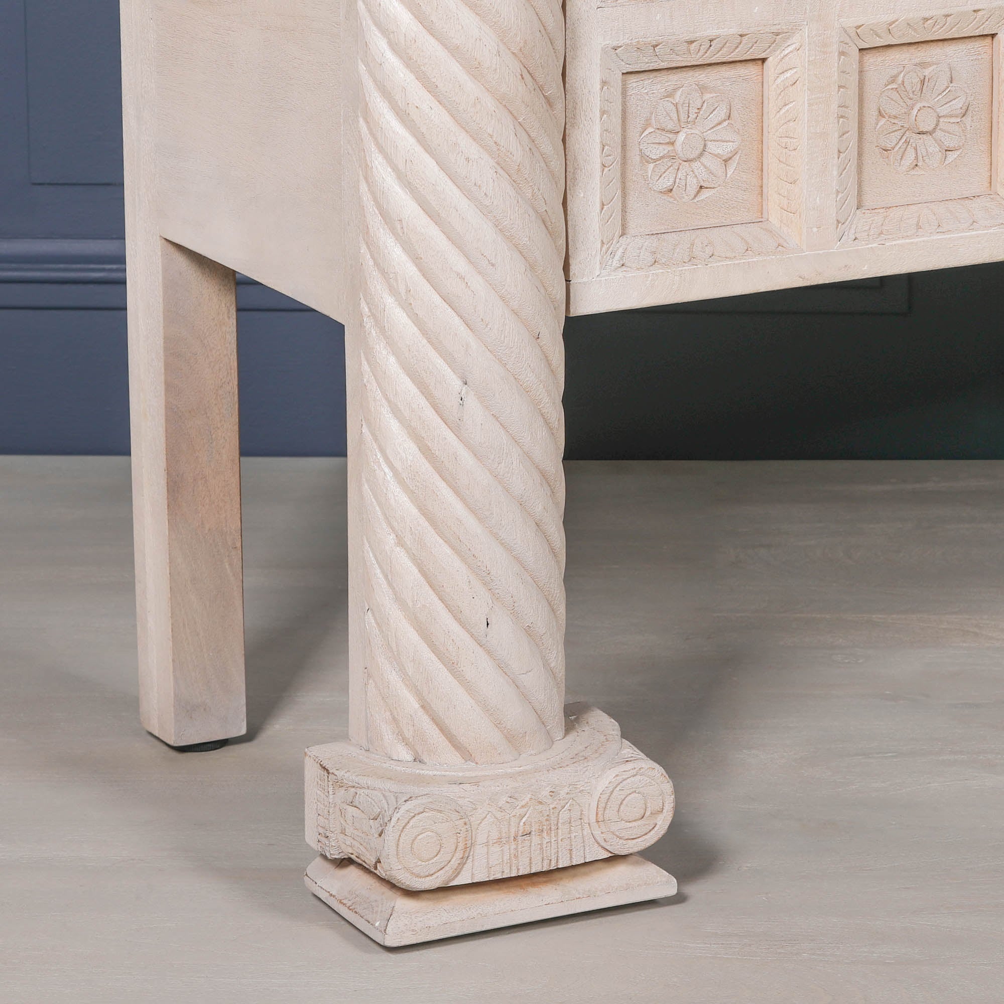 Delphine mango wood reception desk with carved twisted column and floral panels against a dark blue wall