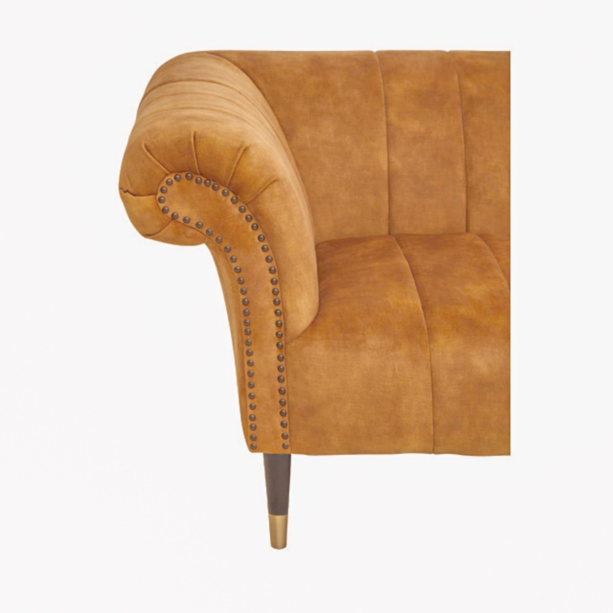 Side profile of the Elara Two Seat Sofa in Gold Velvet Upholstery displaying the sculpted scroll arm, gold velvet upholstery, nailhead trim and elegant tapered wooden leg with brass-effect cap.