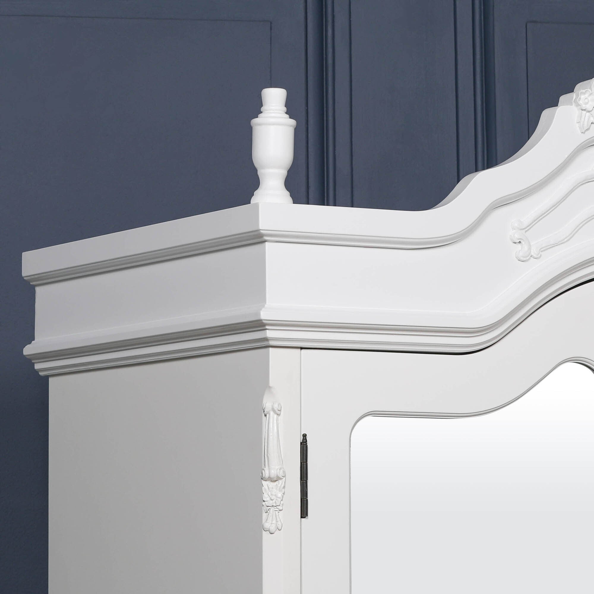 Close-up of the Élodie White Mirrored Double Door Armoire Wardrobe showcasing the ornate hand-carved French Rococo crown, decorative mouldings, painted white finish and exceptional artisan craftsmanship.