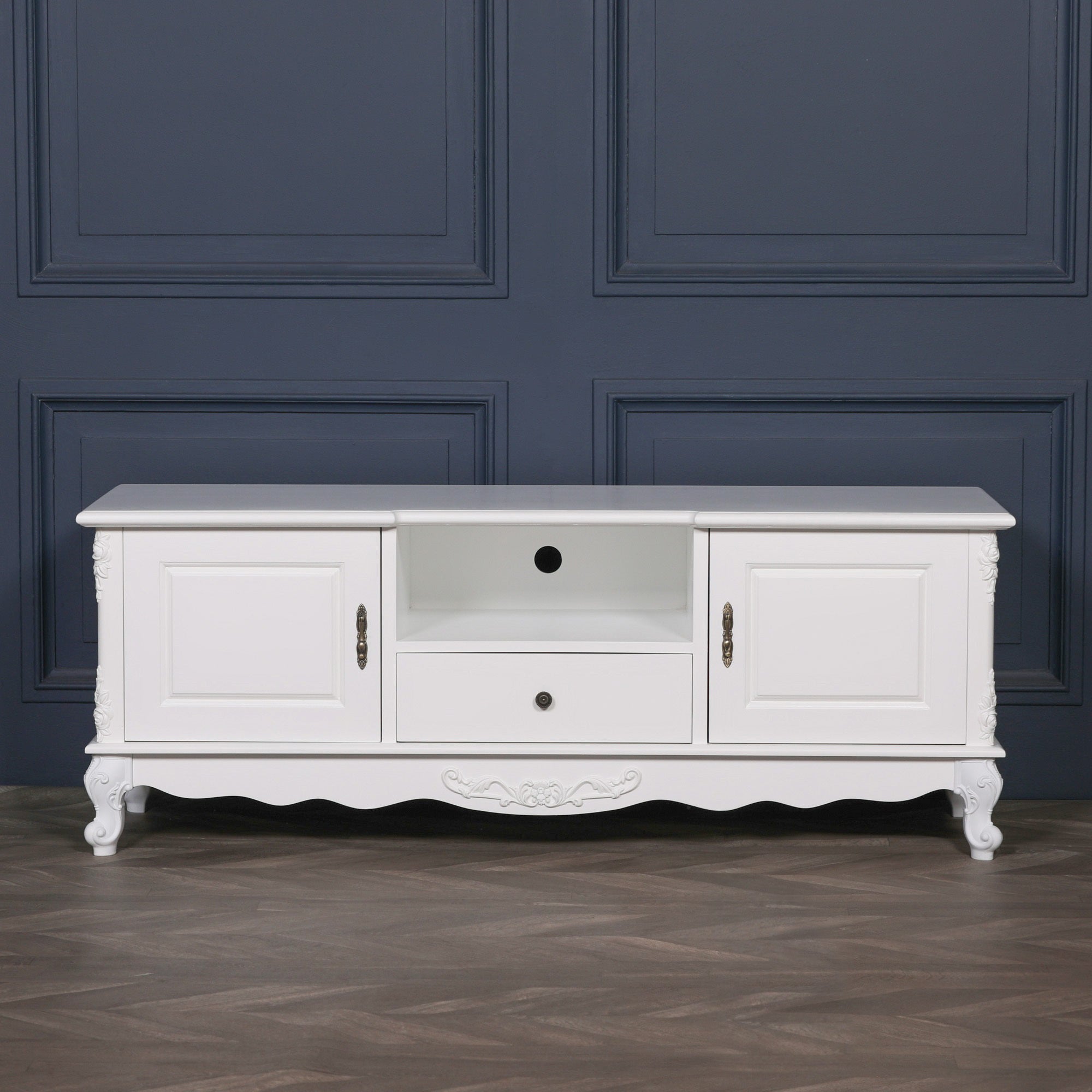 Front view of the Éloise Large French White TV Cabinet with Hand-Carved Detailing against a dark blue interior, highlighting elegant media storage, cupboard doors, central drawer and French styling.