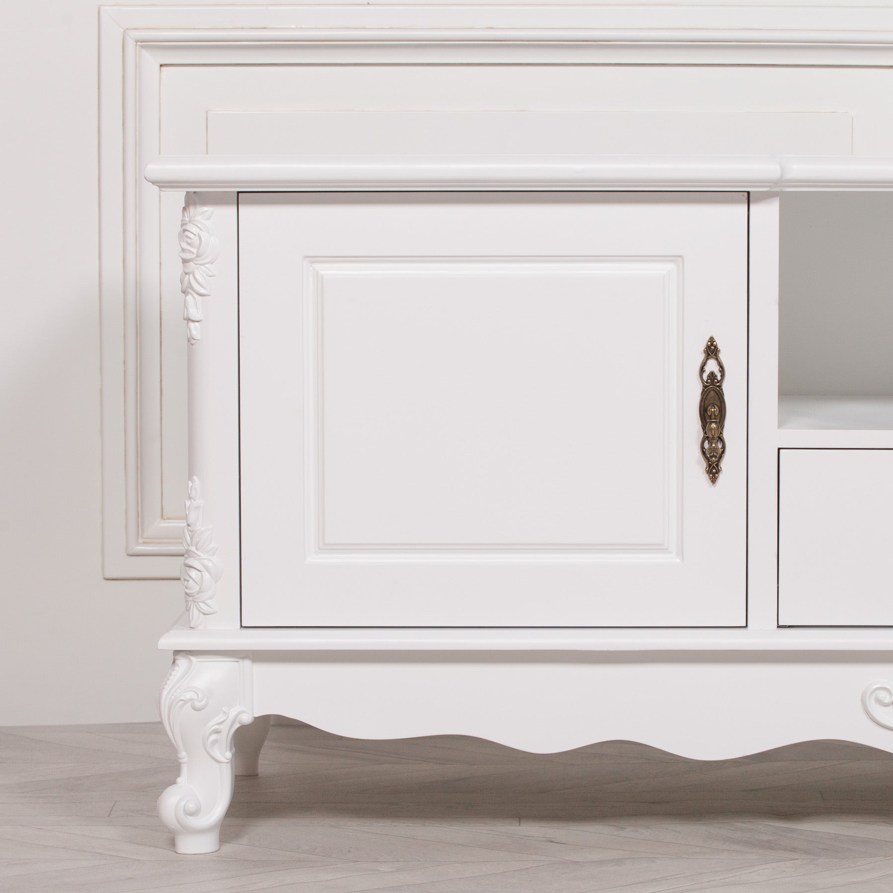 Close-up of the Éloise Large French White TV Cabinet highlighting decorative brass handle, recessed panel door, hand-carved floral embellishments and premium white painted finish.