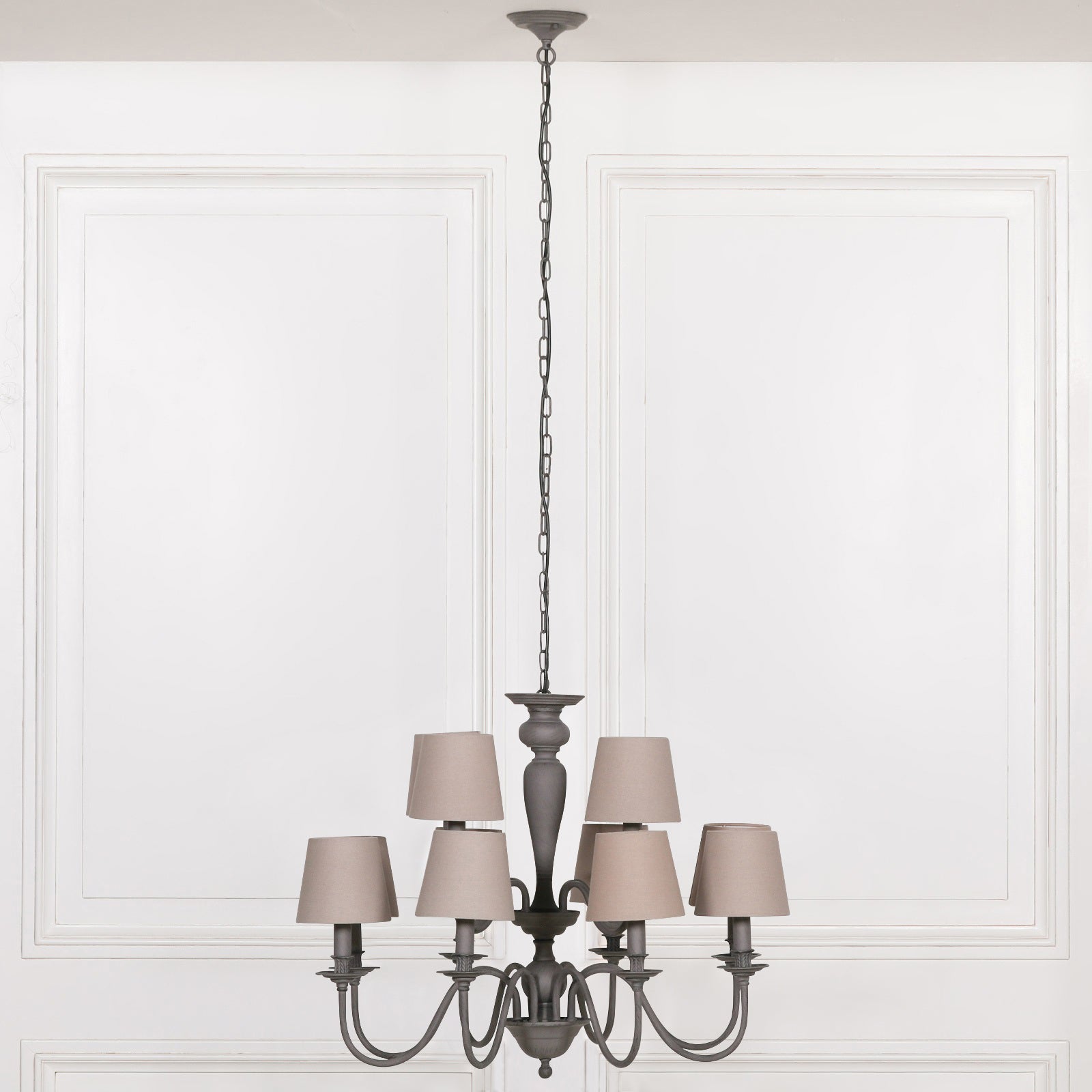 Evrard grey 12 light chandelier with taupe fabric shades and long chain against a white panelled wall.