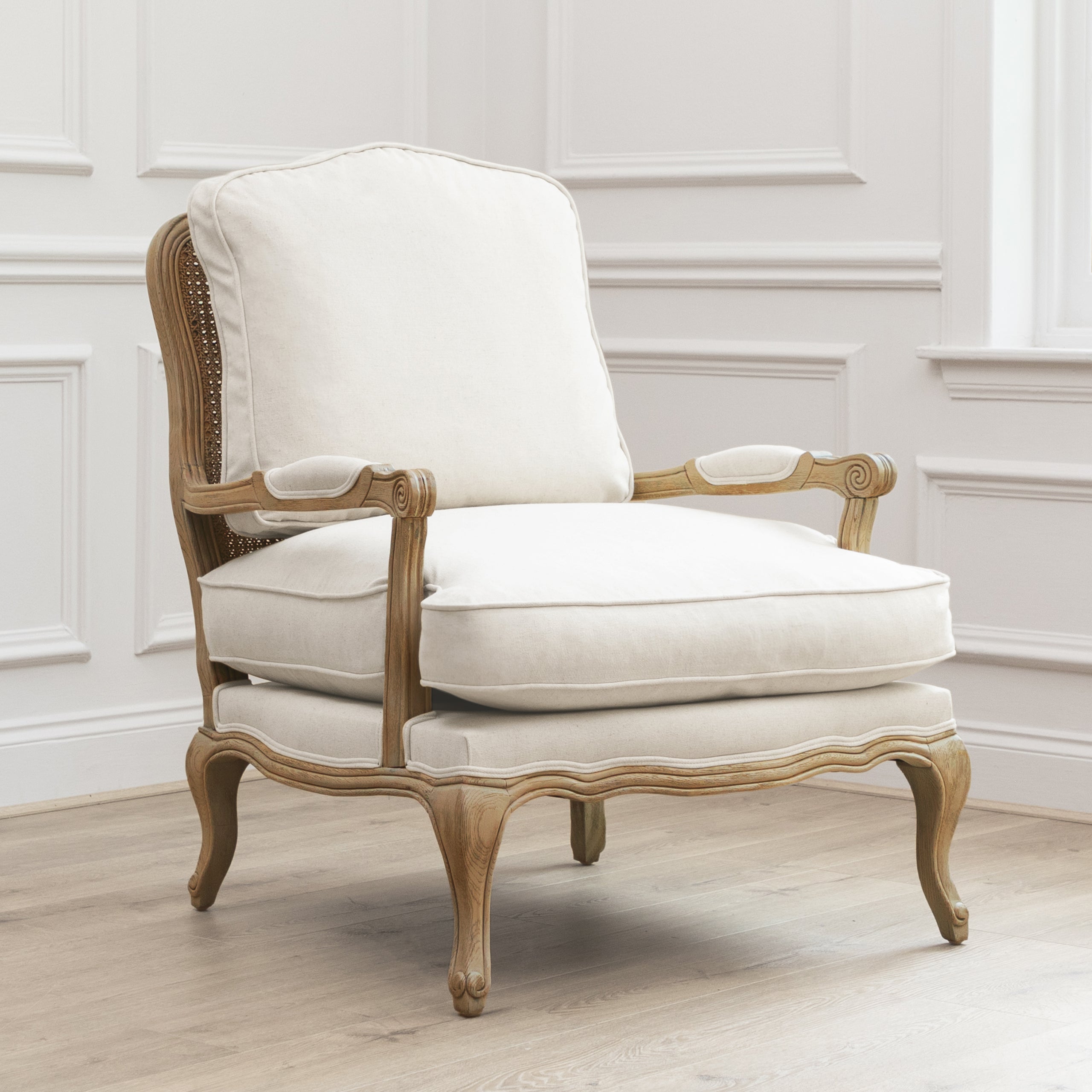 Angled view of Florence cream upholstered oak accent chair against white panelled walls and light wood flooring.