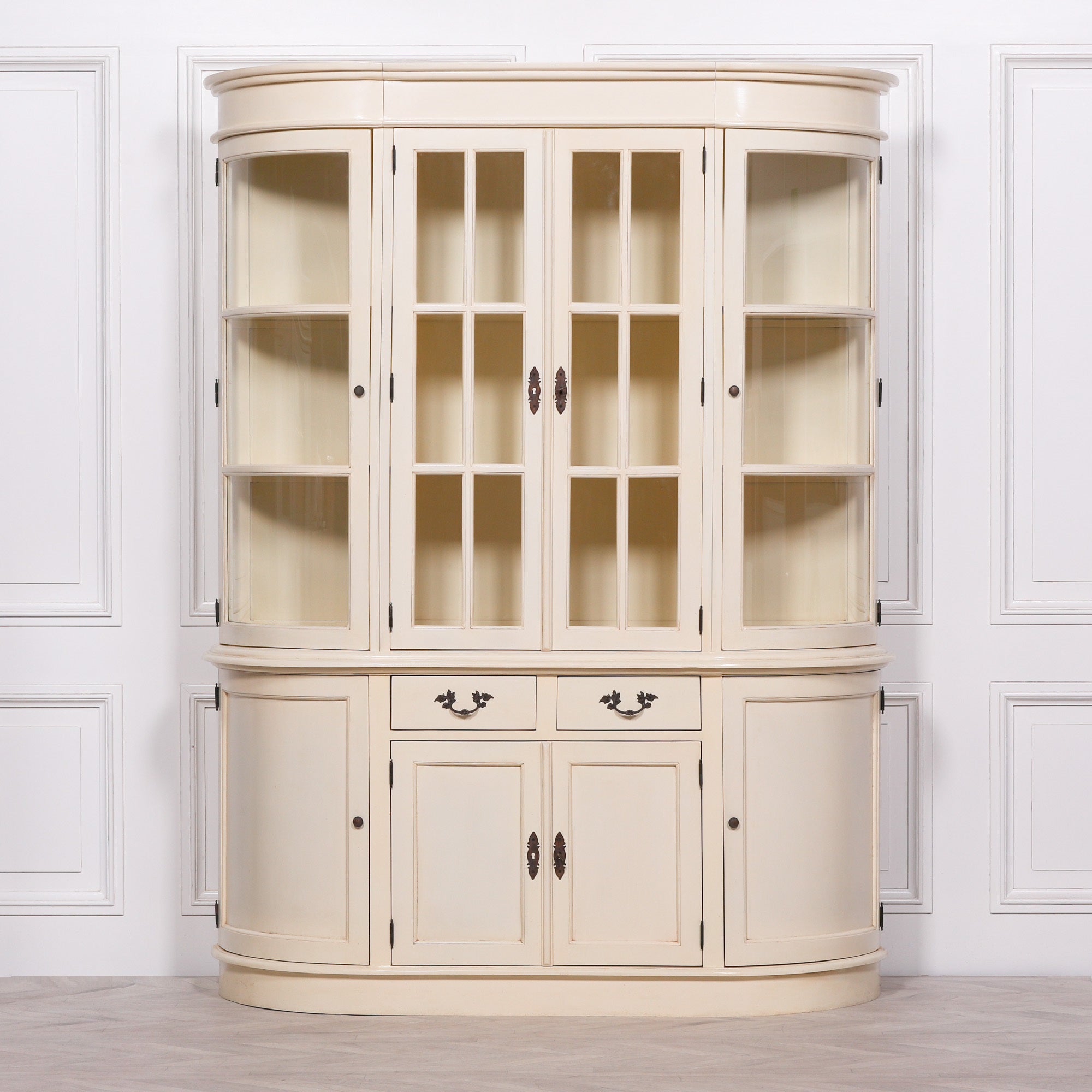 Geneviève 175cm aged cream mahogany display cabinet with glass doors against a white panelled wall.