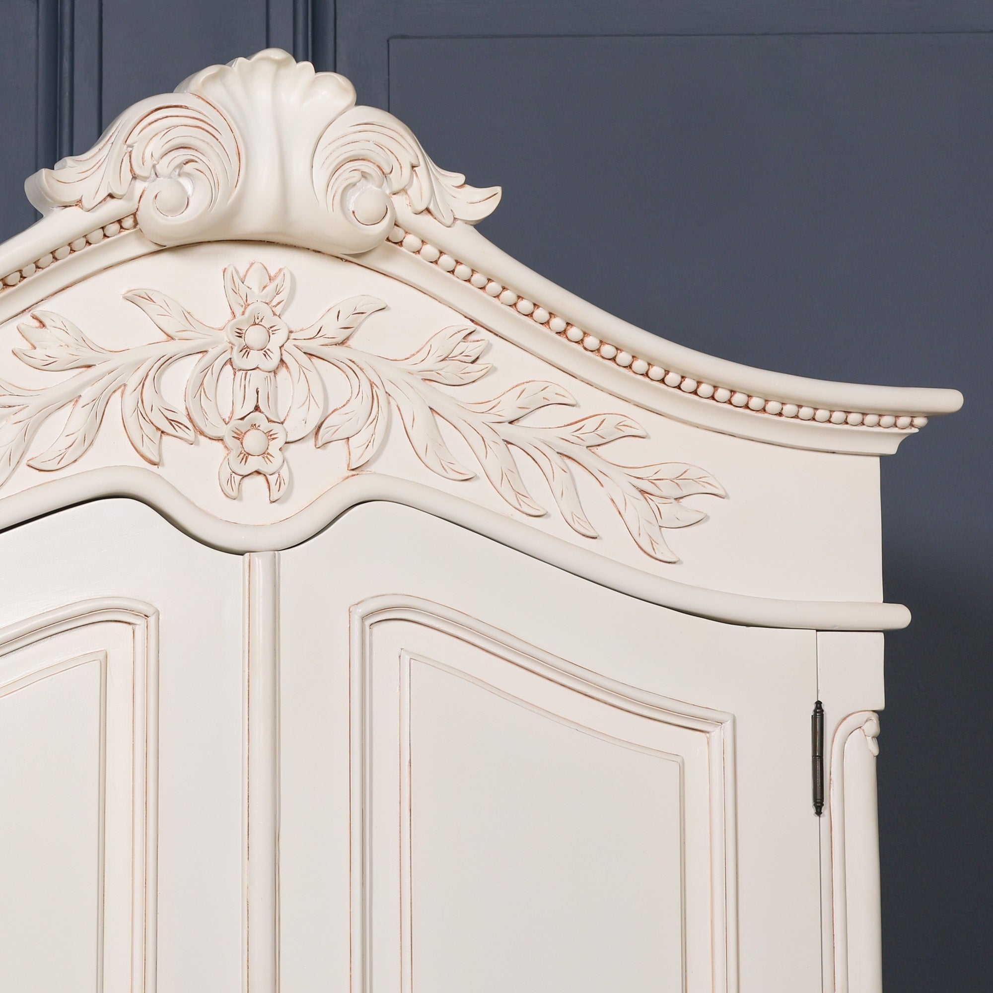Detailed view of the Geneviève Hand-Carved French Chateau Double Door Armoire Wardrobe featuring the ornate French Chateau crown, floral hand carvings, scrollwork and traditional artisan craftsmanship.
