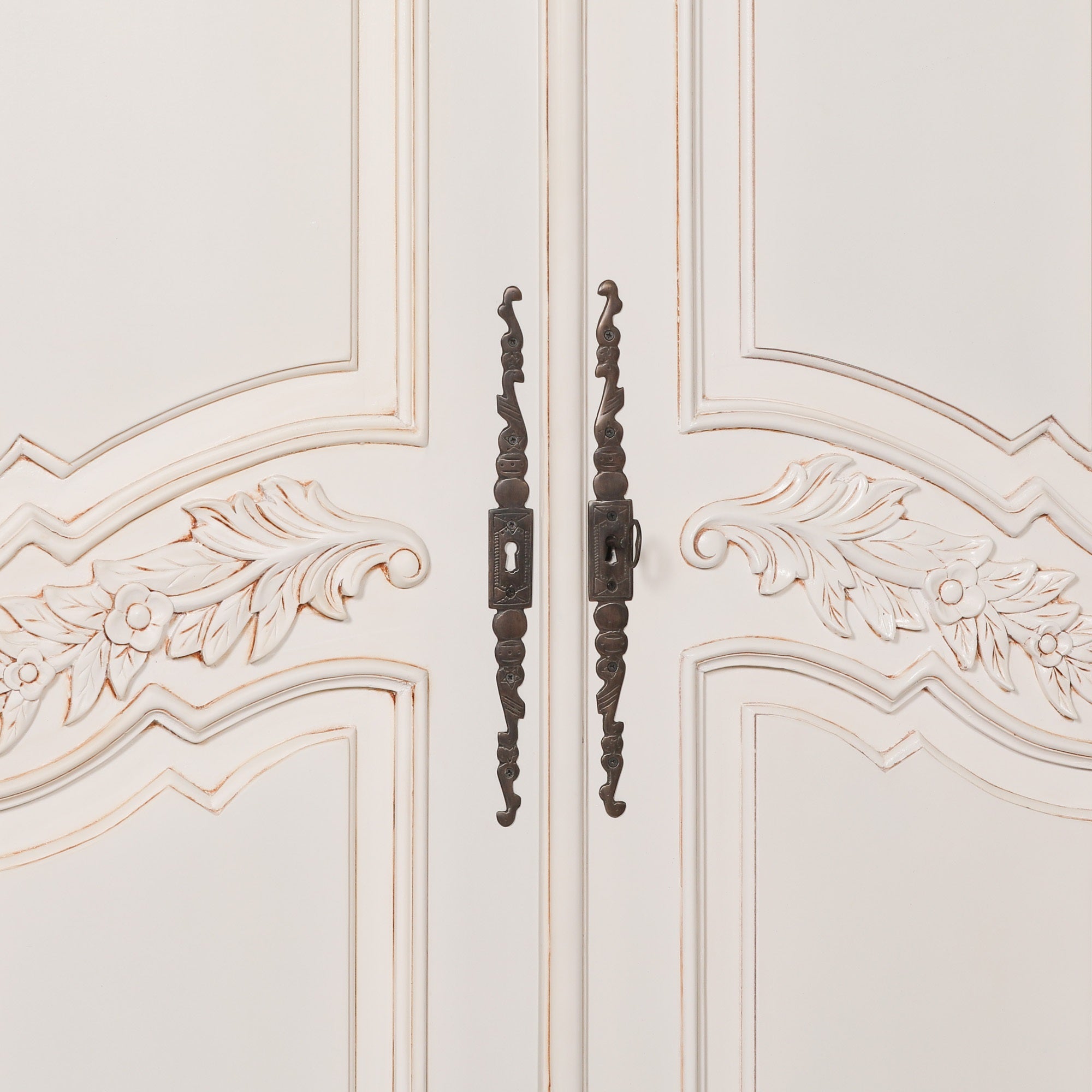 Detailed close-up of the Geneviève Hand-Carved French Chateau Double Door Armoire Wardrobe featuring ornate antique-style metal handles, floral carved door panels and elegant French provincial detailing.