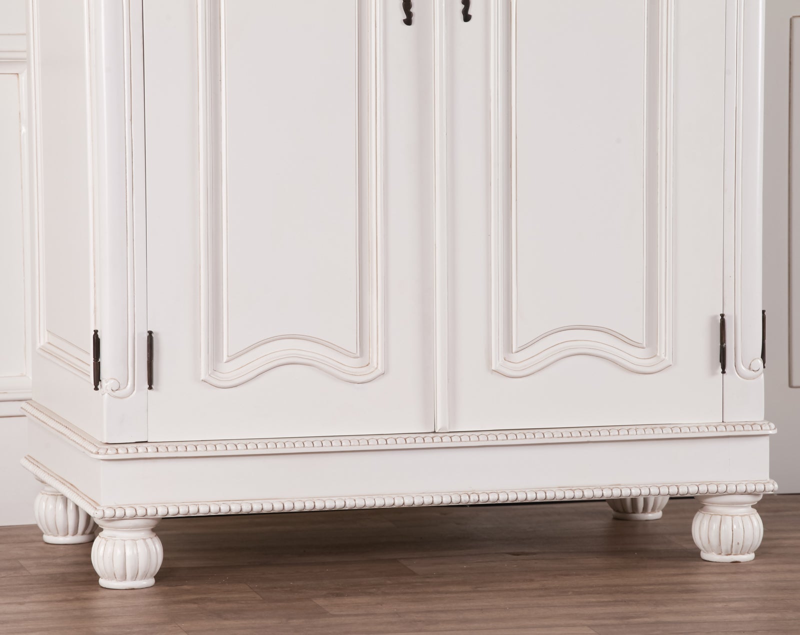 Lower section of the Geneviève Hand-Carved French Chateau Double Door Armoire Wardrobe showcasing decorative bun feet, beaded plinth, carved mahogany construction and traditional French furniture design.