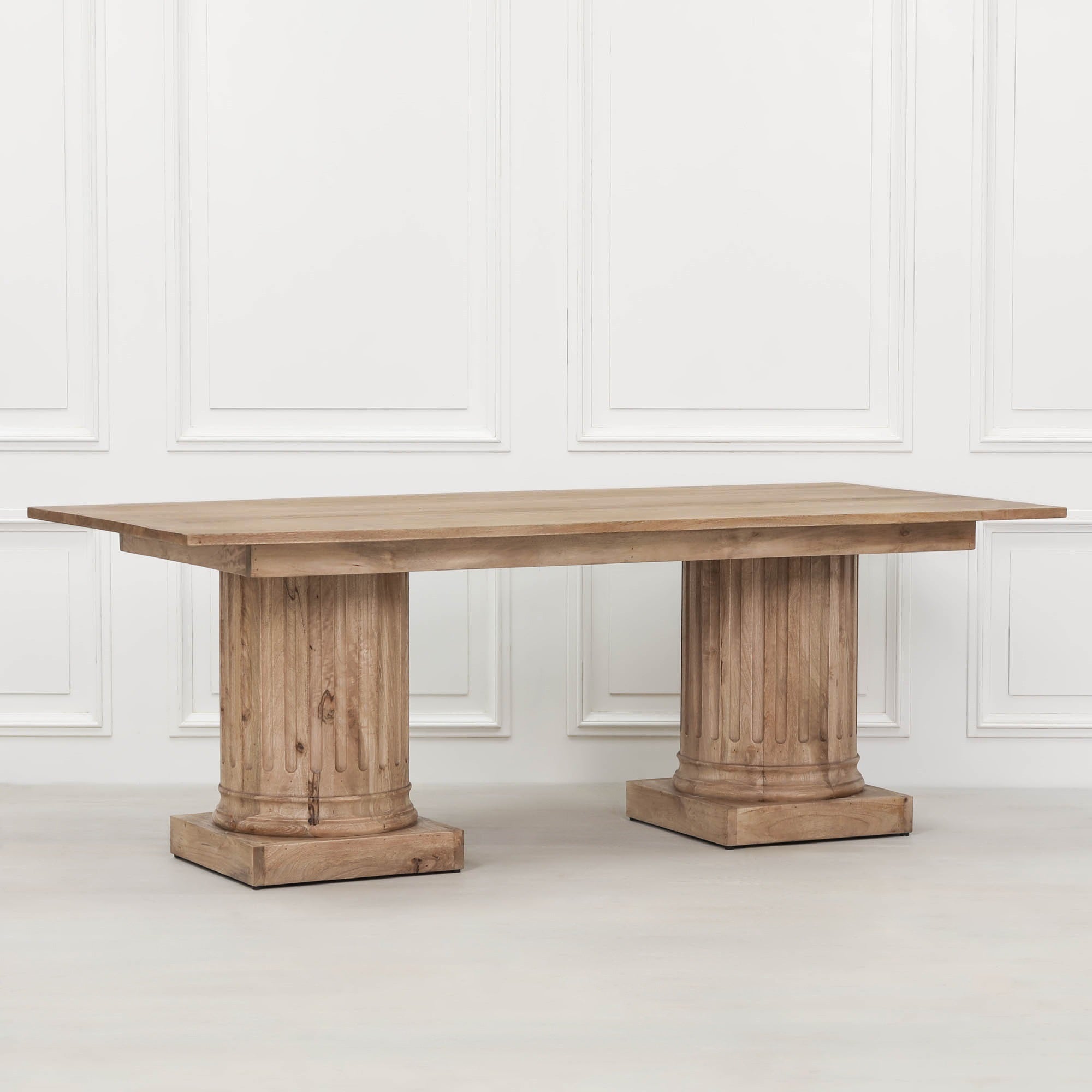 Henri 220cm Rustic Mango Wood Rectangular Column Dining Table photographed at an angle on a white background, highlighting the solid mango wood construction, rustic finish, rectangular tabletop and sculptural fluted column pedestal bases for seating 8 to 10 people.