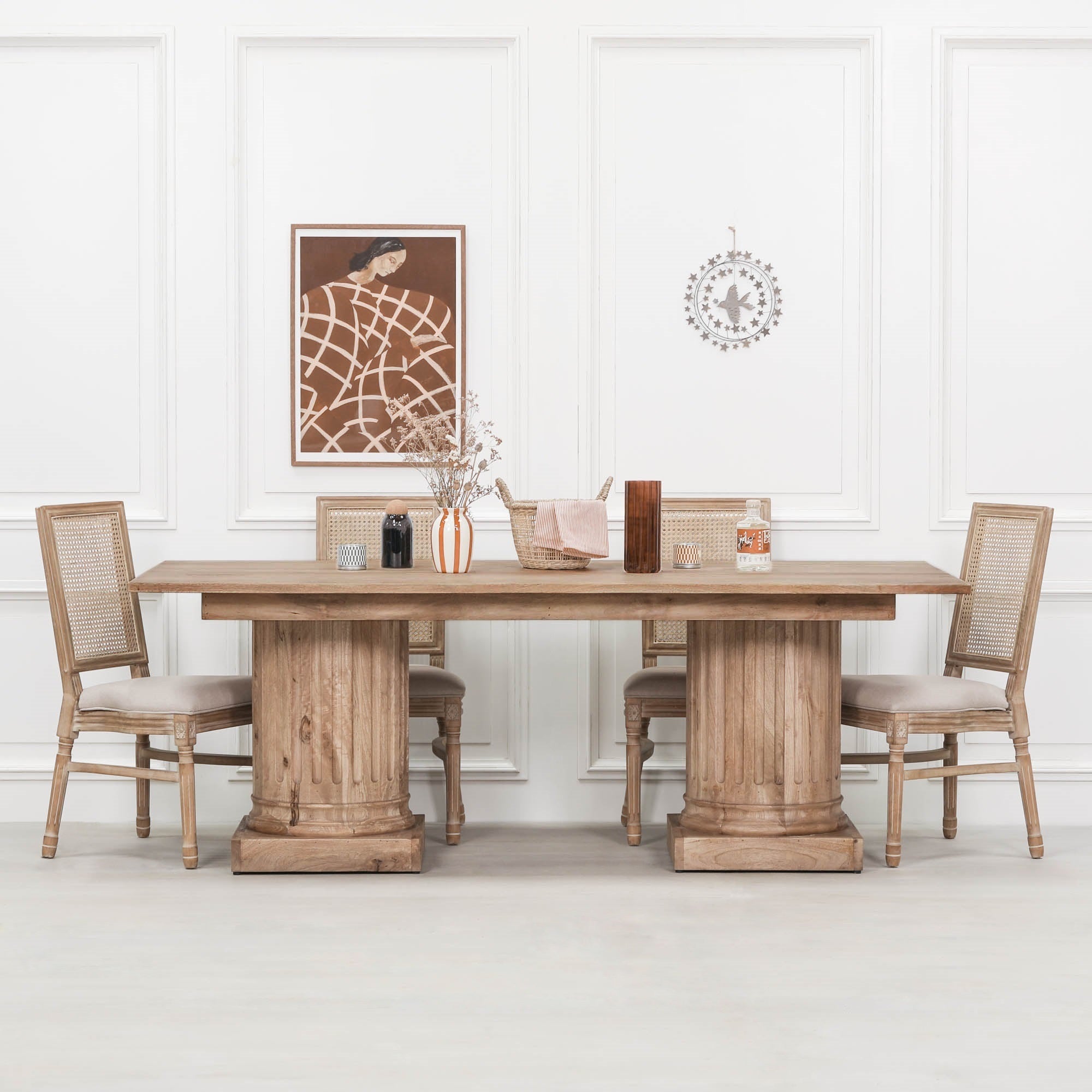 Henri 220cm Rustic Mango Wood Rectangular Column Dining Table styled with woven dining chairs and decorative accessories in a bright dining room, showcasing the rustic mango wood finish, twin column pedestal bases and spacious rectangular design for family dining and entertaining.