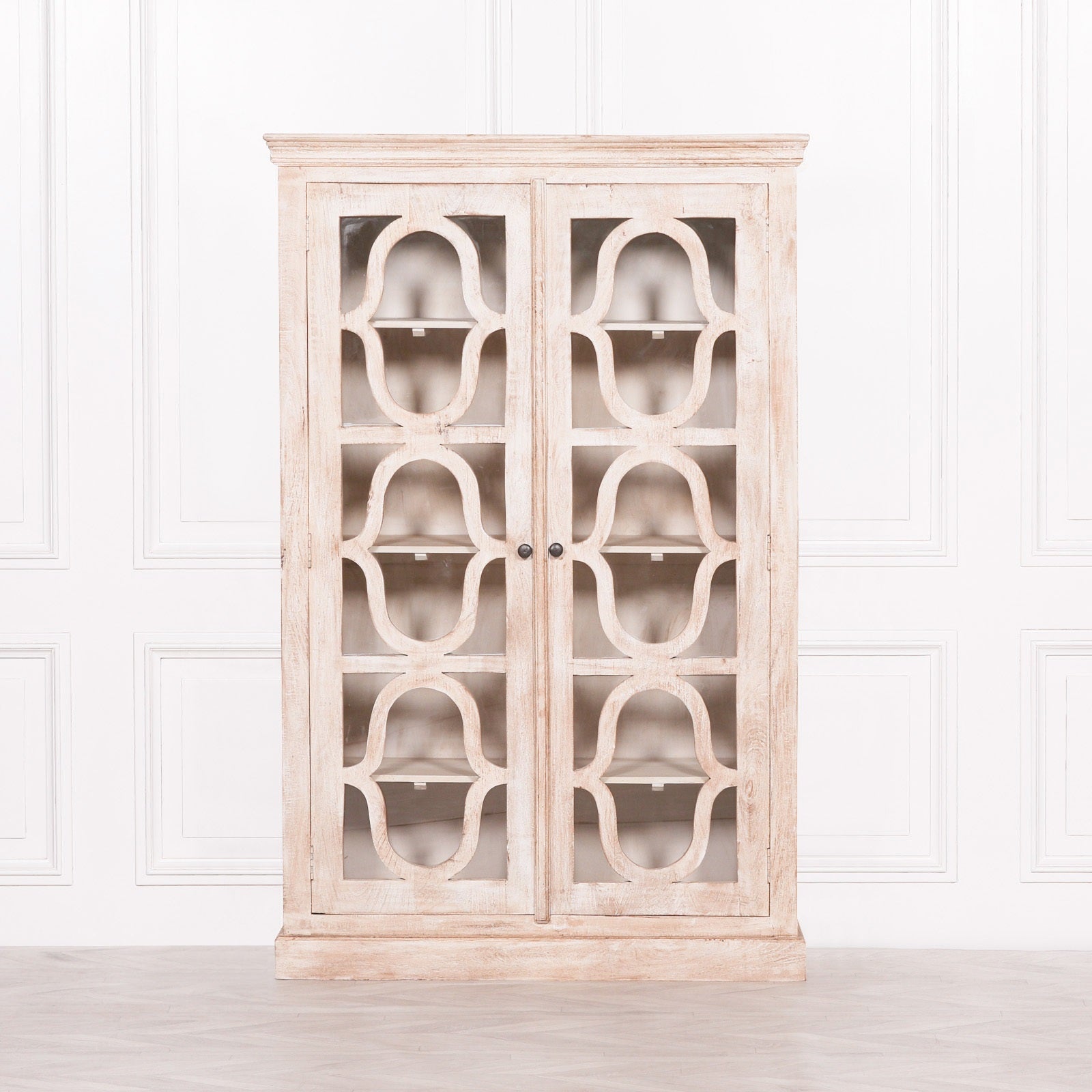 Front view of the Henri Rustic Mango Wood Display Cabinet featuring two ornate glazed doors, handcrafted mango wood construction, generous internal shelving and a timeless rustic finish ideal for displaying glassware, books and decorative accessories.
