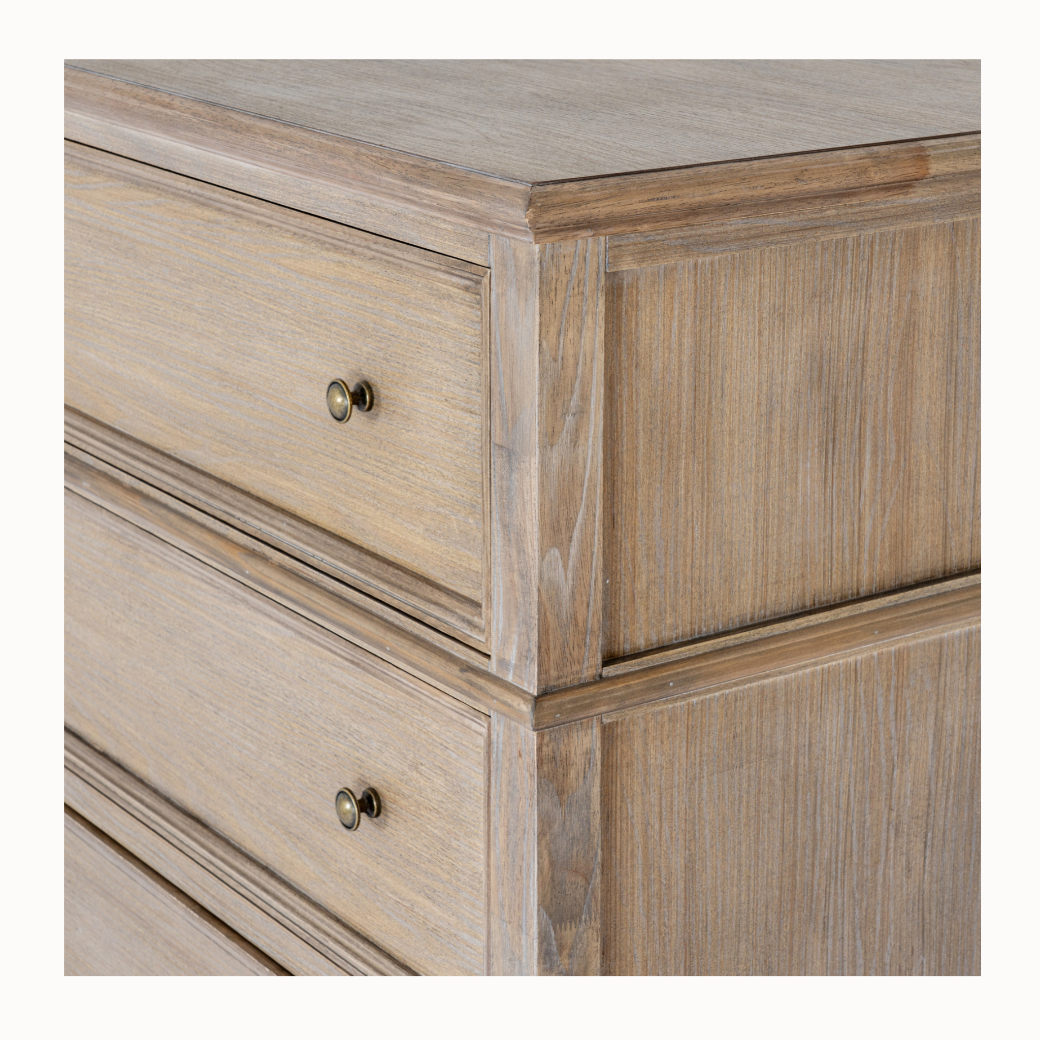 Close-up of Laurent brown wood 5 drawer chest showing wood grain, panelled drawers and brass knobs on white.