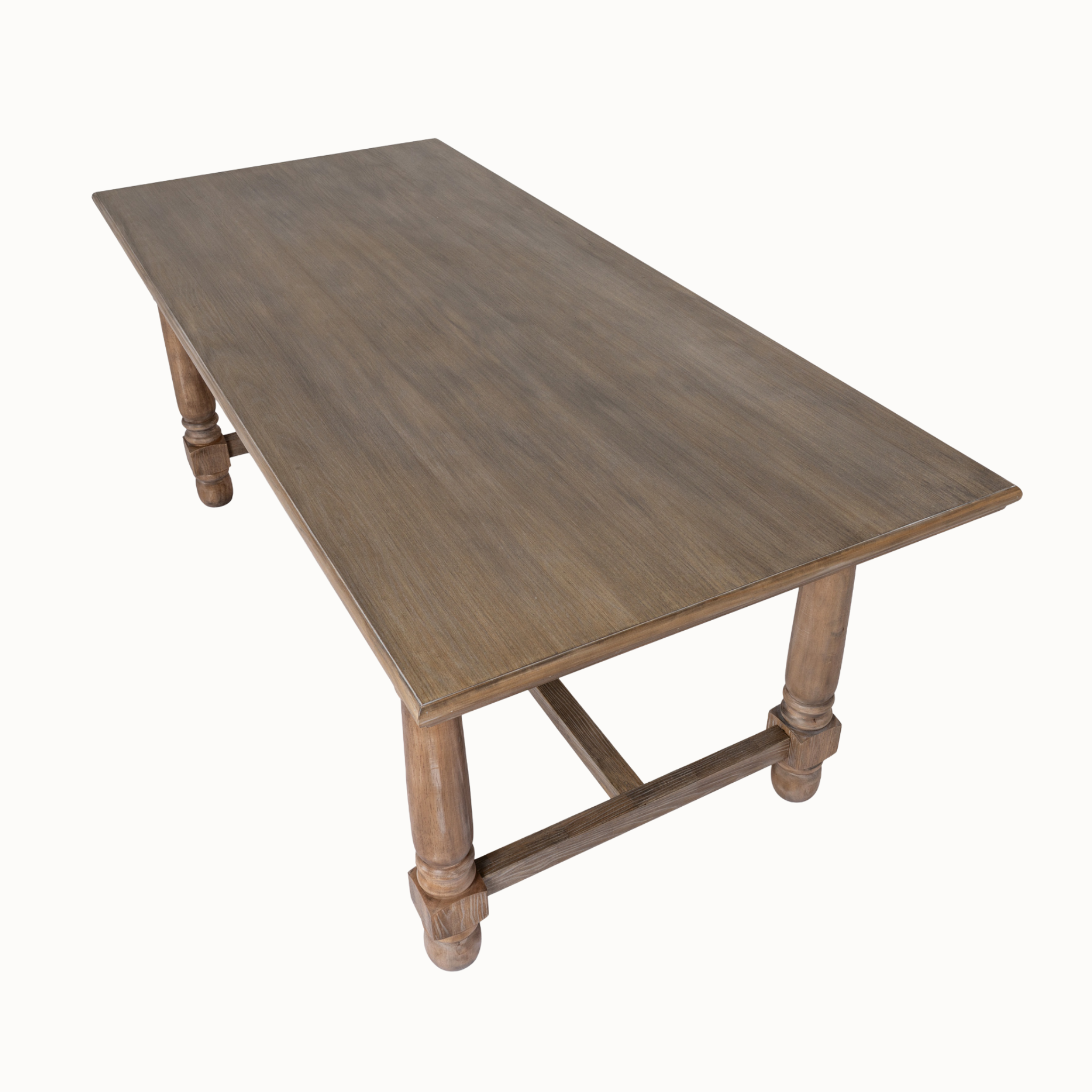 Angled view of Laurent brown wood dining table showing rectangular top, turned legs and stretcher base on white.