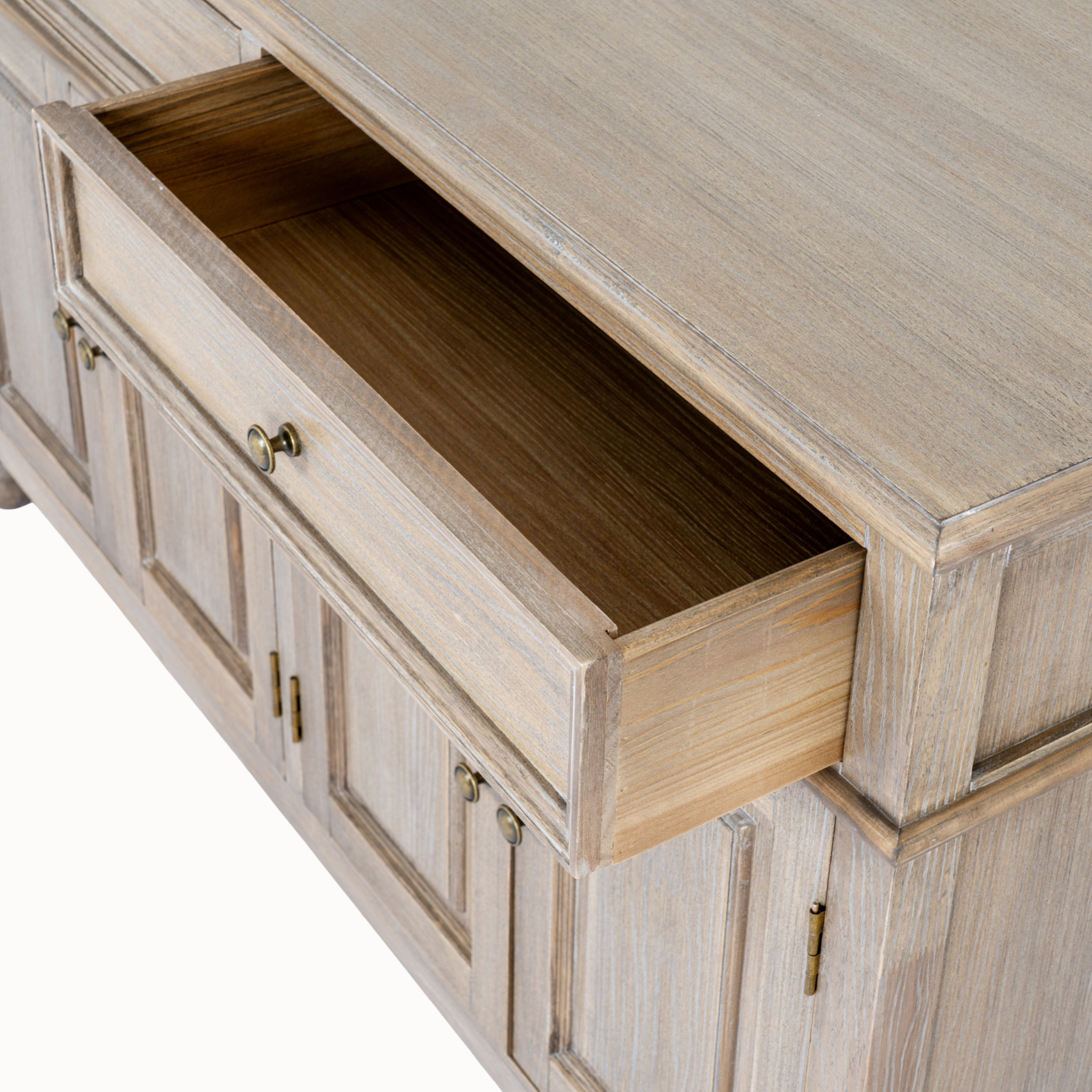 Laurent brown wood sideboard close-up showing an open storage drawer, brass knobs and wood grain on a white background.