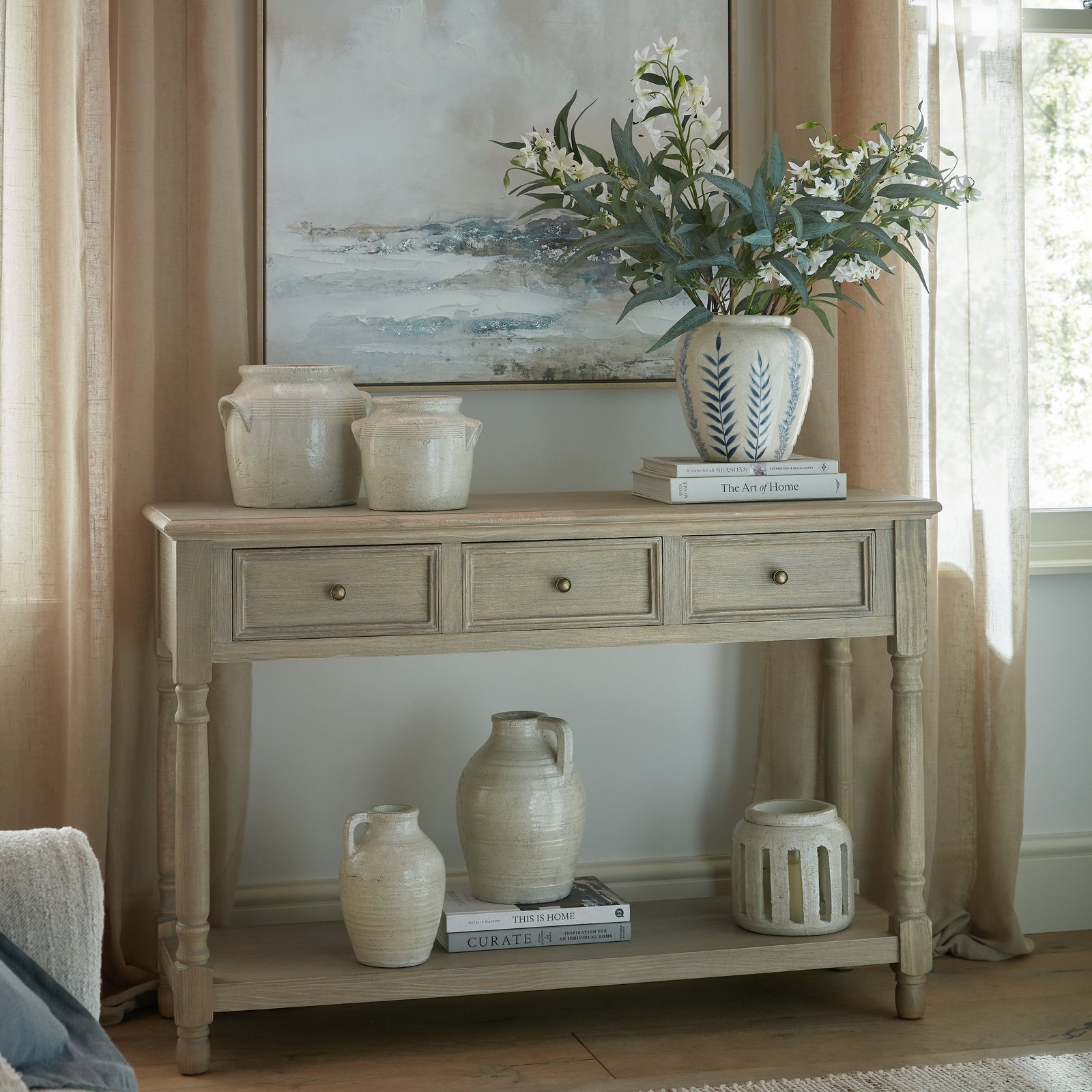 Laurent Wood Console Table with 3 Drawers & Shelf styled in an elegant living room, featuring a natural wood finish, three storage drawers, lower display shelf, turned legs and decorative ceramic accessories for timeless hallway and living room styling.