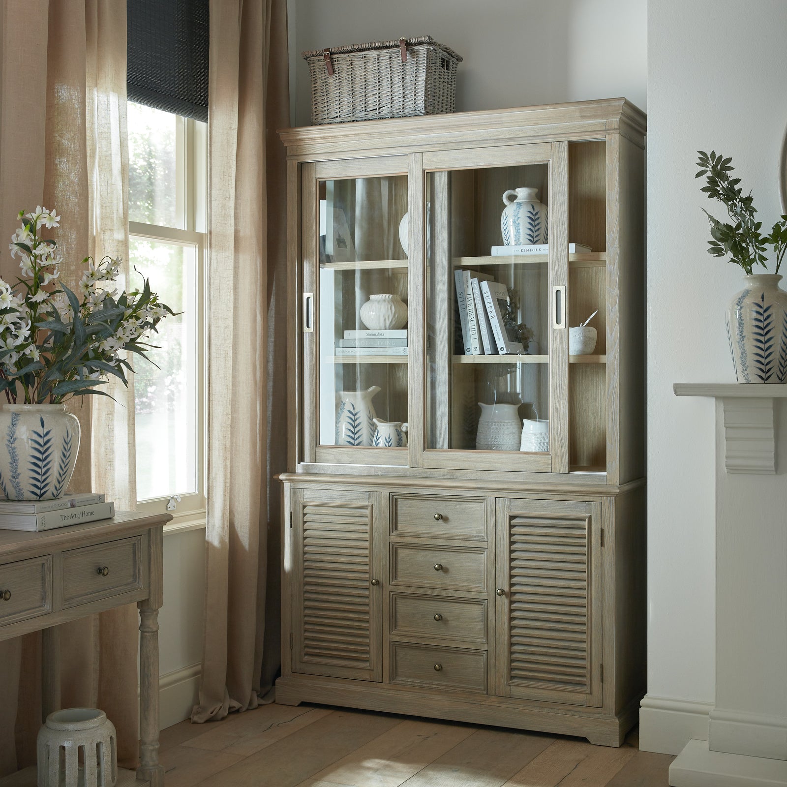 The Laurent Wood Display Cabinet Set with Sliding Glass Doors styled in a contemporary living room, showcasing natural wood craftsmanship, spacious display shelving, decorative storage and elegant glass-front cabinet design.