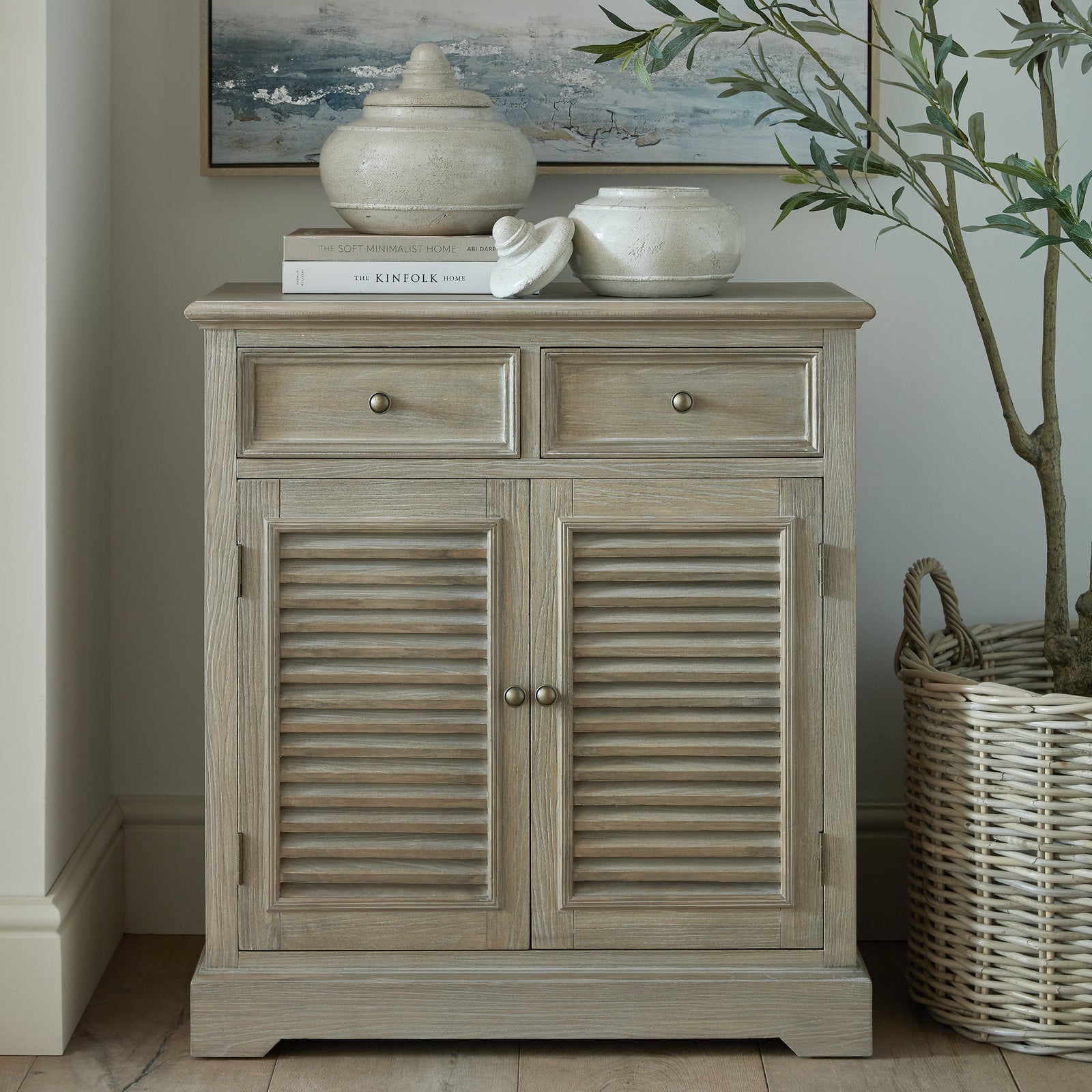 Laurent Wood Storage Chest with 2 Doors & 2 Drawers styled in a contemporary living space, featuring a natural wood finish, louvred cupboard doors, two storage drawers, antique brass knobs and timeless rustic storage furniture for elegant home organisation.