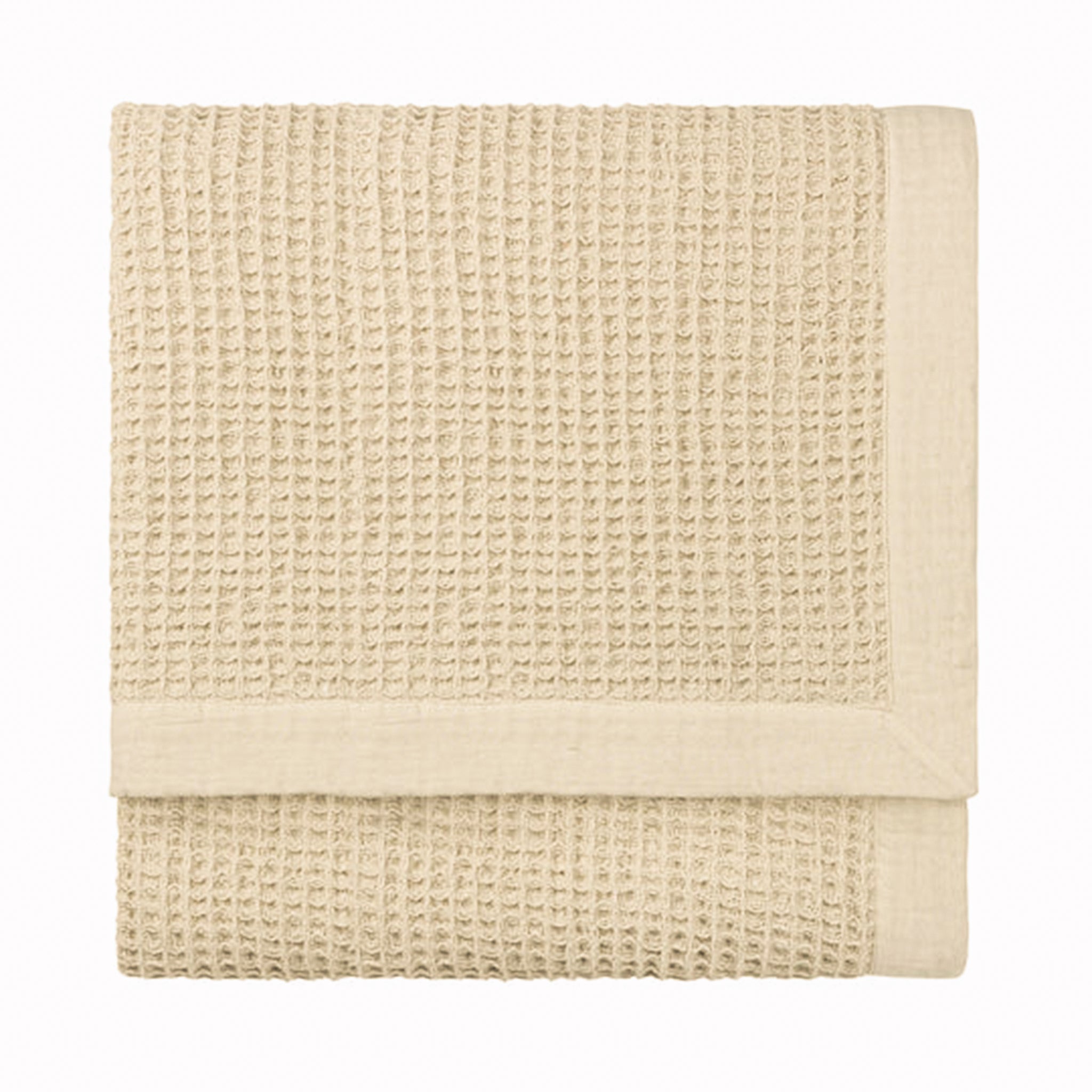 Folded Léna oversized cotton throw in stone and natural, featuring a tactile waffle weave texture with a smooth contrasting border for neutral bedroom and living room styling.