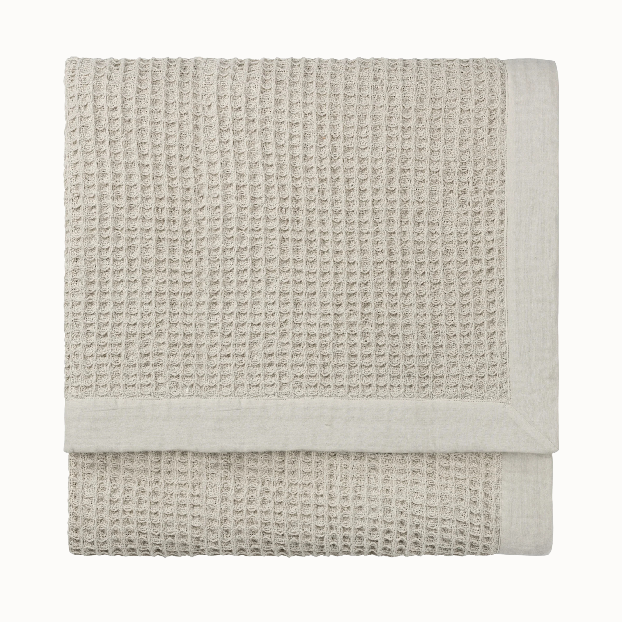 Folded Léna stone waffle weave cotton throw with natural fabric border on a clean white background.